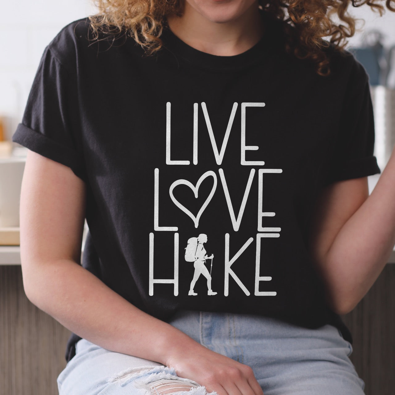 Woman wearing Women's hiking lifestyle shirt Live Love Hike with minimalist stacked typography heart symbol and female hiker silhouette on Comfort Colors tee for outdoor enthusiasts celebrating trail passion and for hikers and foodies