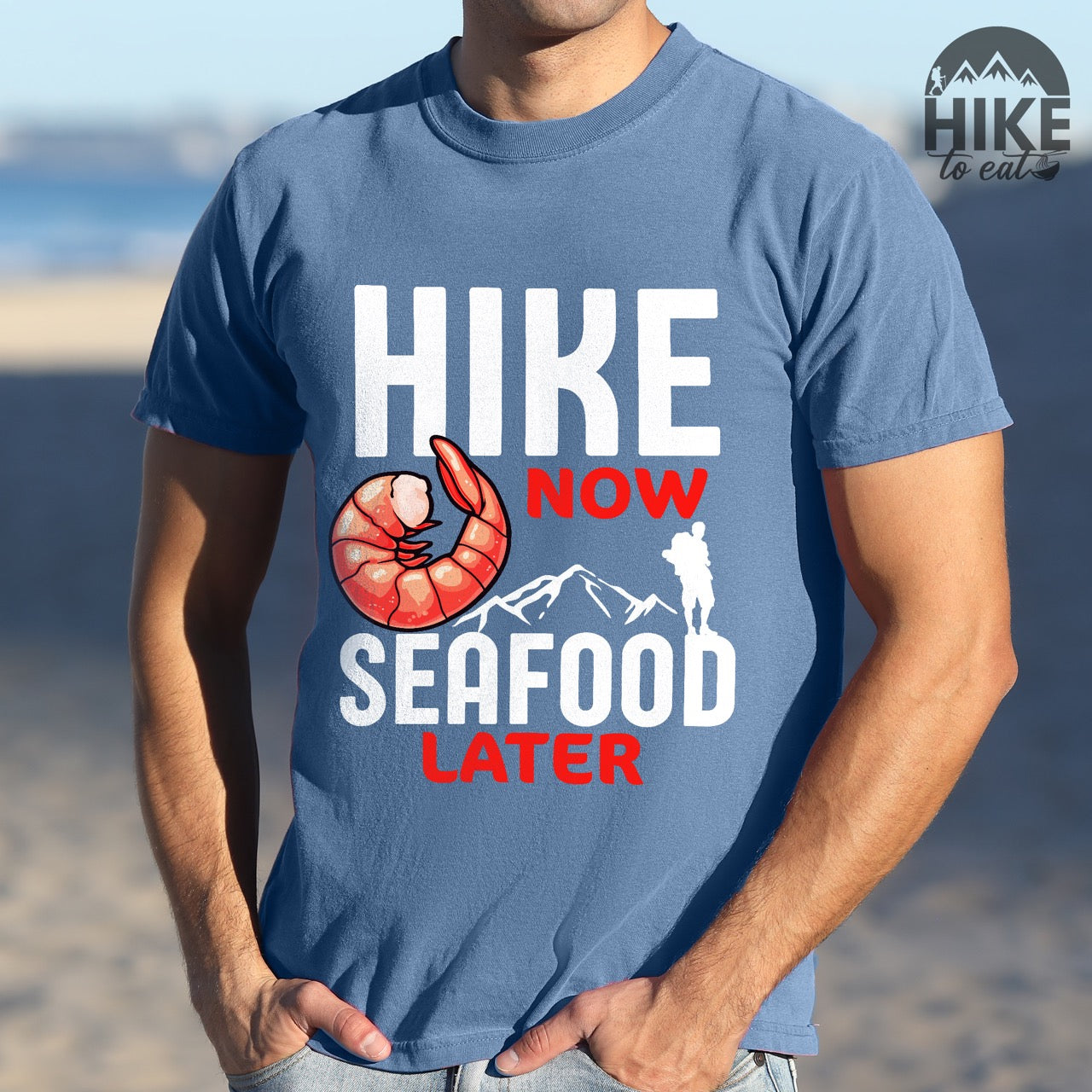man wearing Funny hiking motivation shirt for seafood lovers featuring bold NOW LATER typography, realistic shrimp graphic, mountain landscape illustration, and hiker silhouette on premium outdoor adventure tee perfect gift for trail enthusiasts who love fresh ocean food in blue jean
