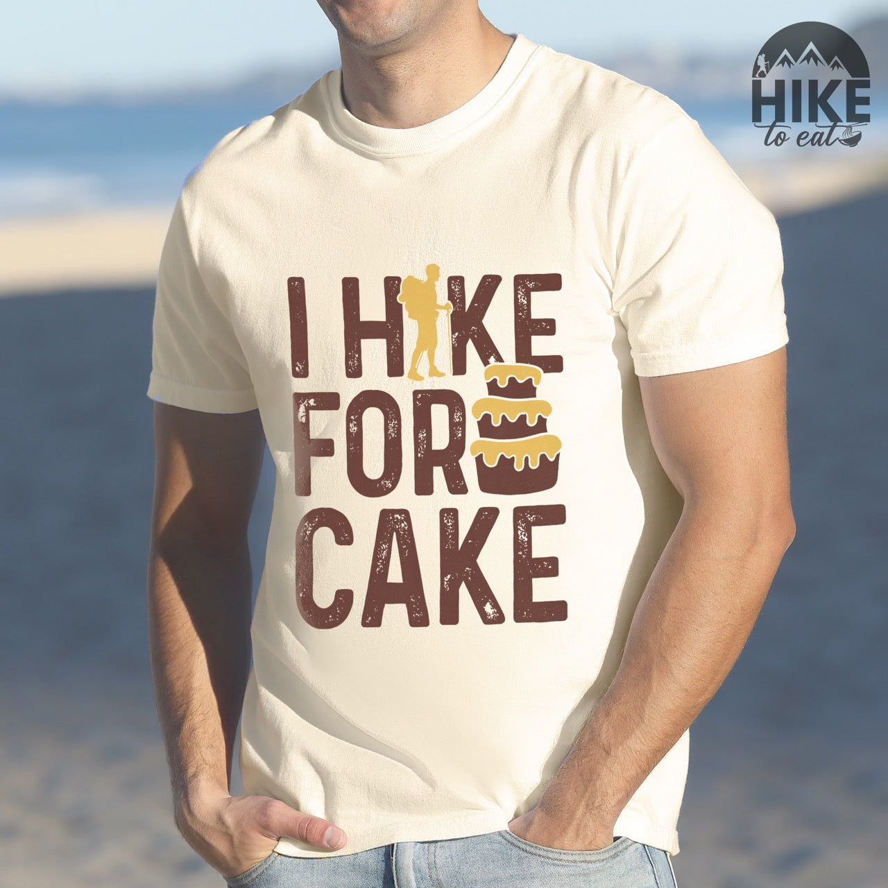 Man wearing ivory I Hike for Cake vintage statement tee with brown typography, hiker silhouette, and layered cake illustration on Comfort Colors shirt