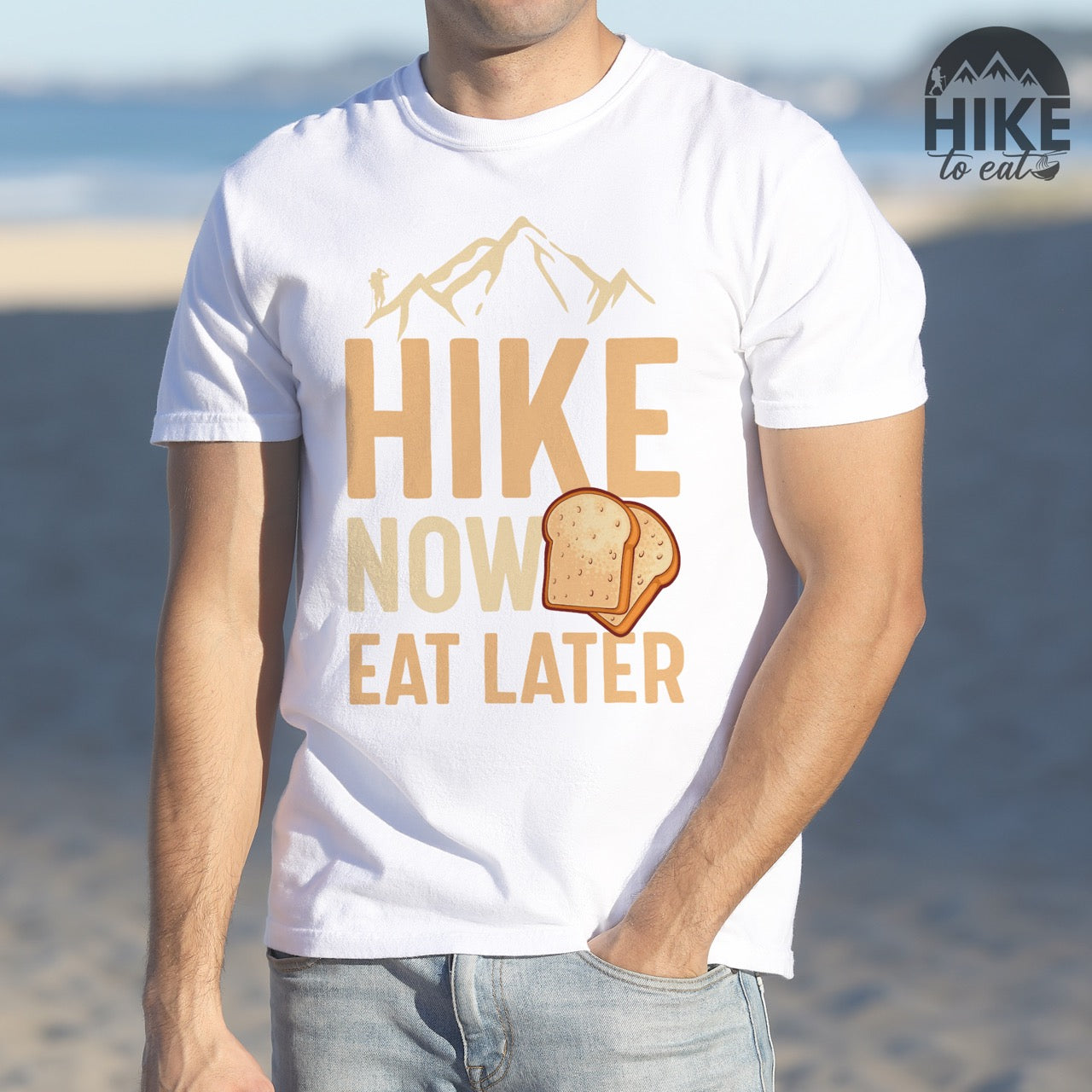 Man wearing white Food motivation vintage tee Hike Now Eat Later with mountain peak range character silhouette bold typography and illustrated toast slices on Comfort Colors shirt for delayed gratification adventure enthusiasts, food lovers and hikers.