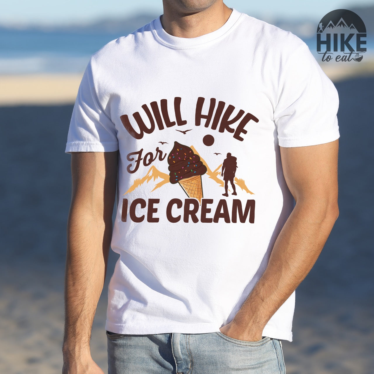 White Will Hike for Ice Cream statement tee with curved typography, script lettering, mountain peaks, hiker silhouette, and ice cream cone illustration on Comfort Colors shirt for dessert-loving outdoor enthusiasts
