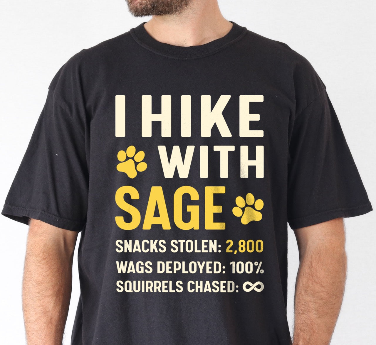 Man wearing black Personalized dog hiking shirt I Hike with custom pet name of Sage featuring paw print graphic, funny adventure statistics including snacks stolen of 2,800, wags deployed and squirrels chased on Comfort Colors tee for outdoor pet lovers