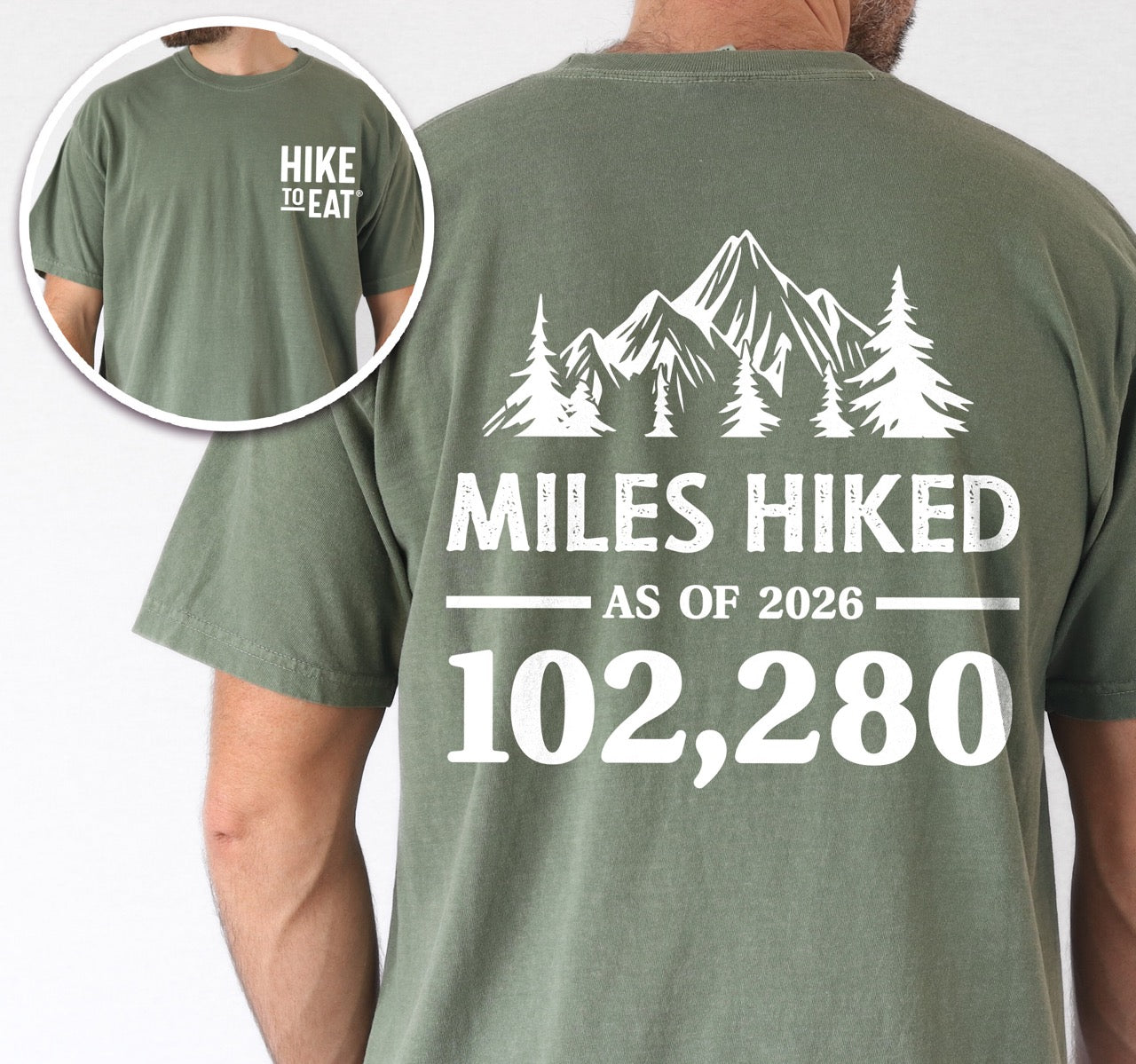 Man wearing Moss (green) t-shirt with Hike to Eat logo on front chest, back featuring MILES HIKED AS OF 2026 text with personalized number field, mountain and pine tree silhouettes, customizable achievement tracker design - perfect for hikers.