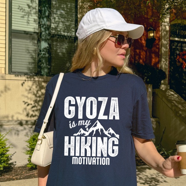 Woman wearing navy blue Gyoza is my Hiking Motivation statement t-shirt with bold distressed typography, mountain peaks, and hiker silhouette for gyoza lovers and outdoor enthusiasts on Gildan 64000 Softstyle 100% cotton