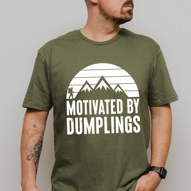 man wearing military green Motivated by Dumplings retro statement tee with sunset design, mountain peaks, and hiker silhouette for dumpling lovers