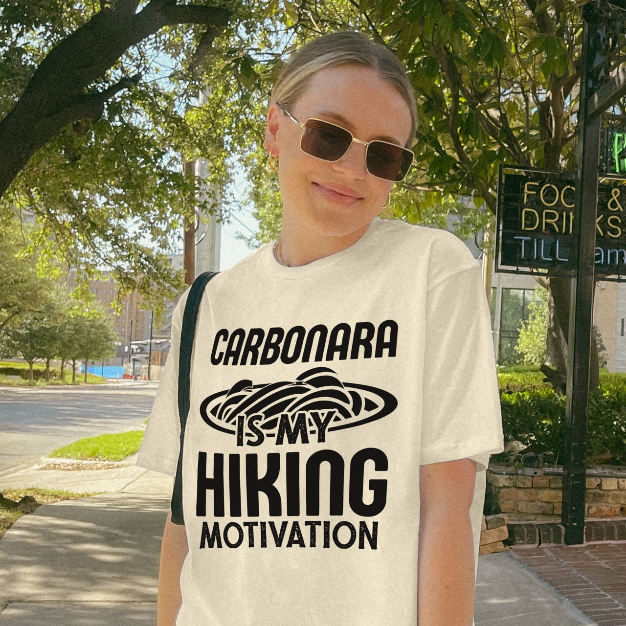 Woman wearing Natural (beige) Carbonara is my Hiking Motivation statement tee with bold typography and pasta bowl illustration for carbonara enthusiasts and hikers