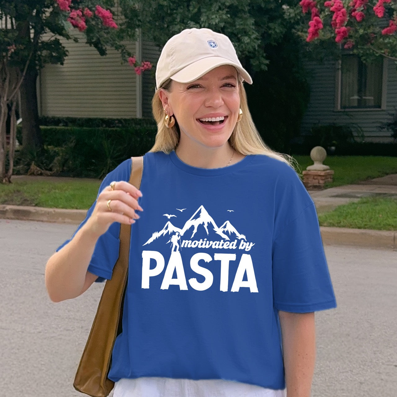 woman laughing while wearing royal (blue) motivated by Pasta statement tee with mountains, birds, and hiker silhouette for pasta enthusiasts and hikers