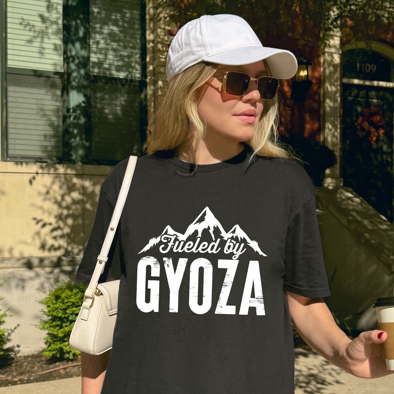 woman wearing black Fueled by Gyoza statement tee with distressed bold typography and mountain peaks for dumpling enthusiasts and hikers