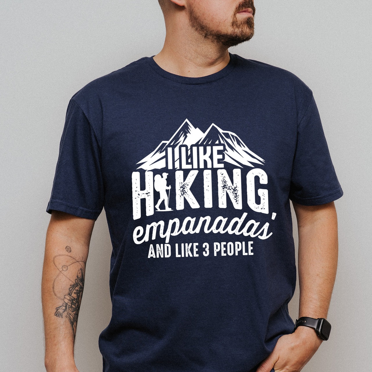 man wearing navy I like Hiking, Empanadas and like 3 People funny introvert statement tee with mountain peaks, hiker silhouette, and distressed typography for empanada-loving outdoor enthusiasts and hikers
