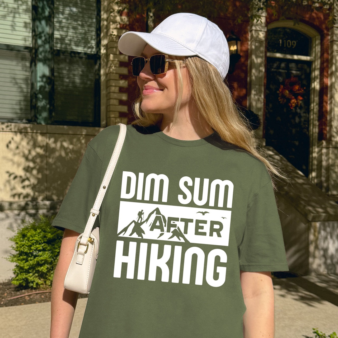 woman wearing Military Green Dim Sum after Hiking statement tee with bold typography, mountain peaks, hiker silhouette, and flying birds for Chinese food-loving outdoor enthusiasts, hikers and foodies