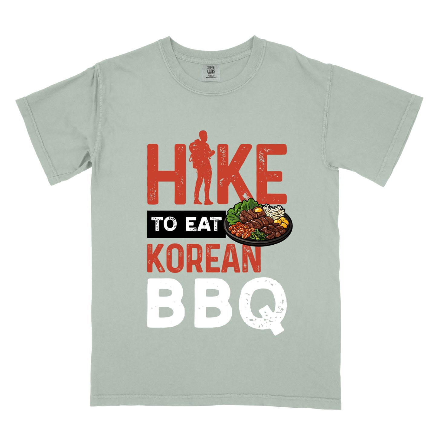 Bay (Light Gray) t-shirt with red and white distressed text reading "HIKE TO EAT KOREAN BBQ". "HIKE" appears in large red letters at the top with a red hiker silhouette integrated into the letter "I", "TO EAT" in white text on a black rectangular background in the middle, "KOREAN" in red, and "BBQ" in white at the bottom. Features an illustration of Korean barbecue with meat and vegetables on a black plate extending from the black background.