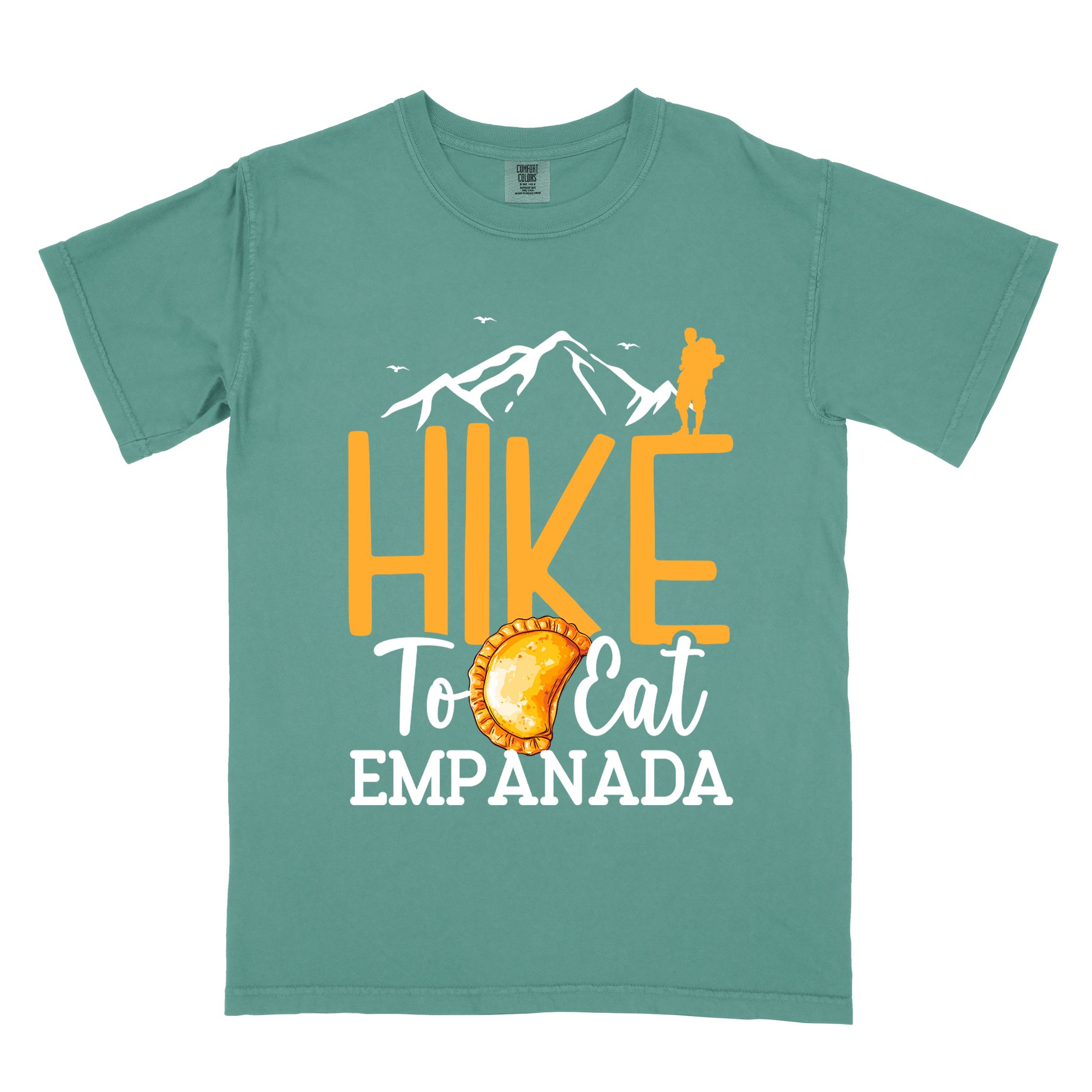 Light green "Hike to eat empanada" colored vintage tee with bold typography, illustrated freshly baked empanada, mountains, birds, and backpackers for street food enthusiasts.