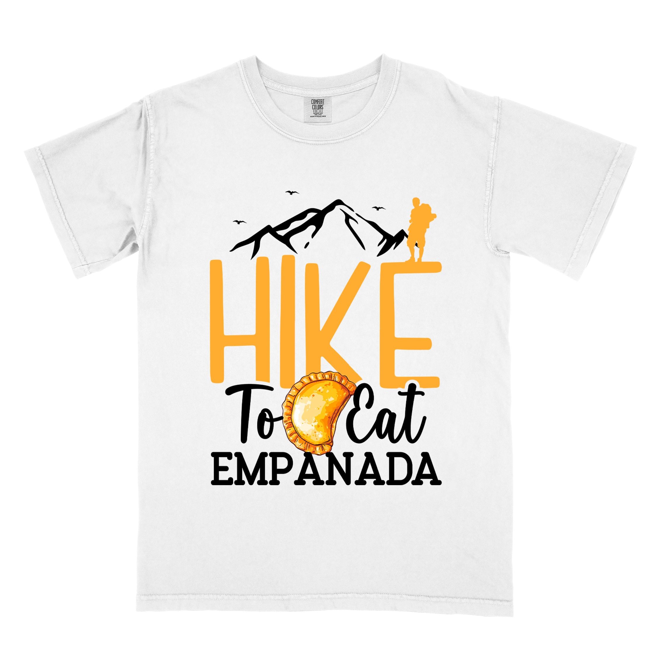 White "Hike to eat empanada" colored vintage tee with bold typography, illustrated freshly baked empanada, mountains, birds, and backpackers for street food enthusiasts.