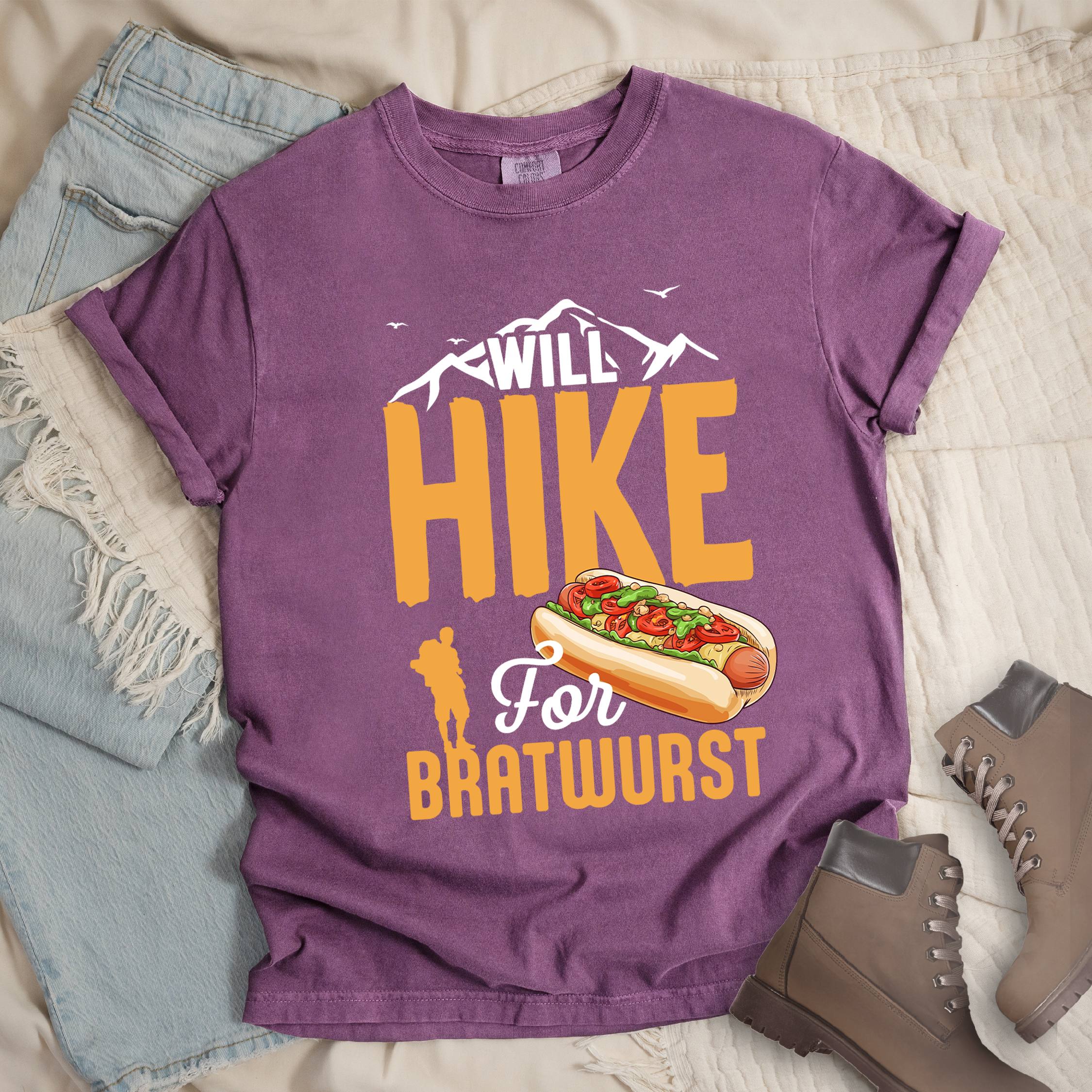 Dark pink shirt with Hiking Design featuring the phrase “Will Hike for Bratwurst” and an illustration of a bratwurst in a bun topped with vegetables.