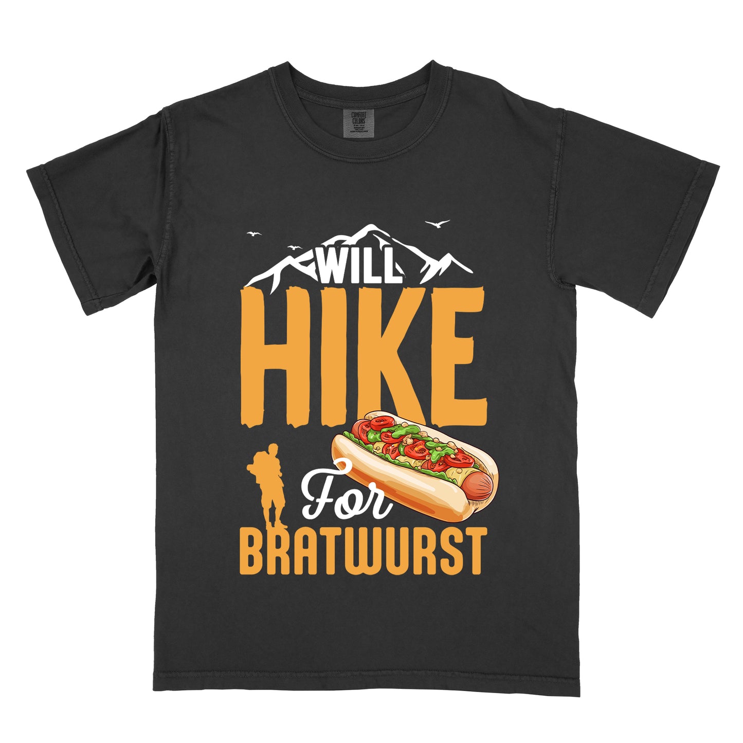 Black t-shirt with white, golden orange, and white text reading "WILL HIKE For BRATWURST". "WILL" appears in white text integrated with mountain outlines at the top, "HIKE" in large golden orange letters in the middle, "For" in white script below it, and "BRATWURST" in golden orange at the bottom. Features an illustration of a bratwurst in a bun with toppings to the right of "For" and a golden orange silhouette of a hiker to the left of "BRATWURST". Small white birds fly near the mountains.