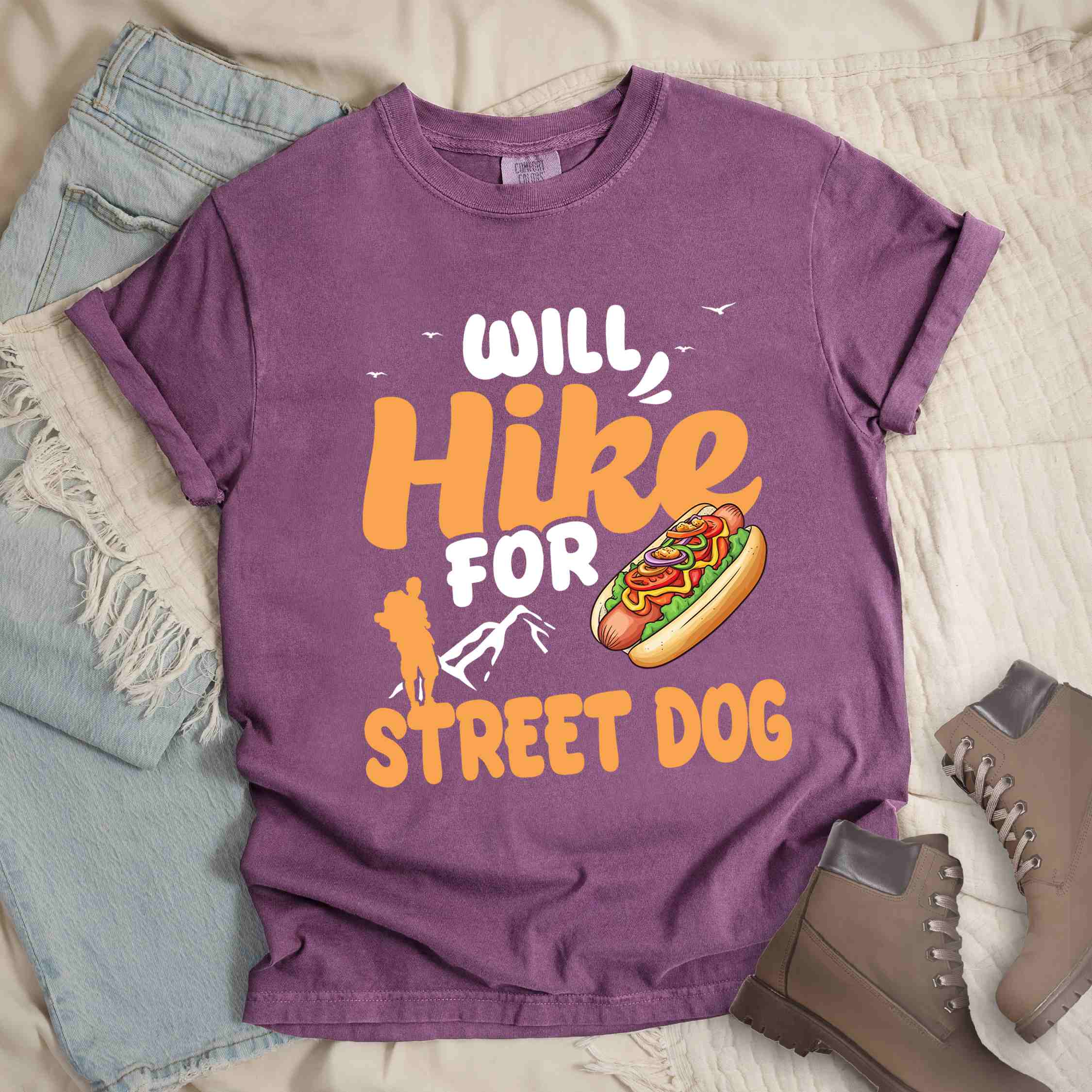 Berry "Will hike for street dog" colored vintage tee with bold typography, illustrated freshly bratwurst in a bun, mountains, birds, and backpackers for street dog lovers.