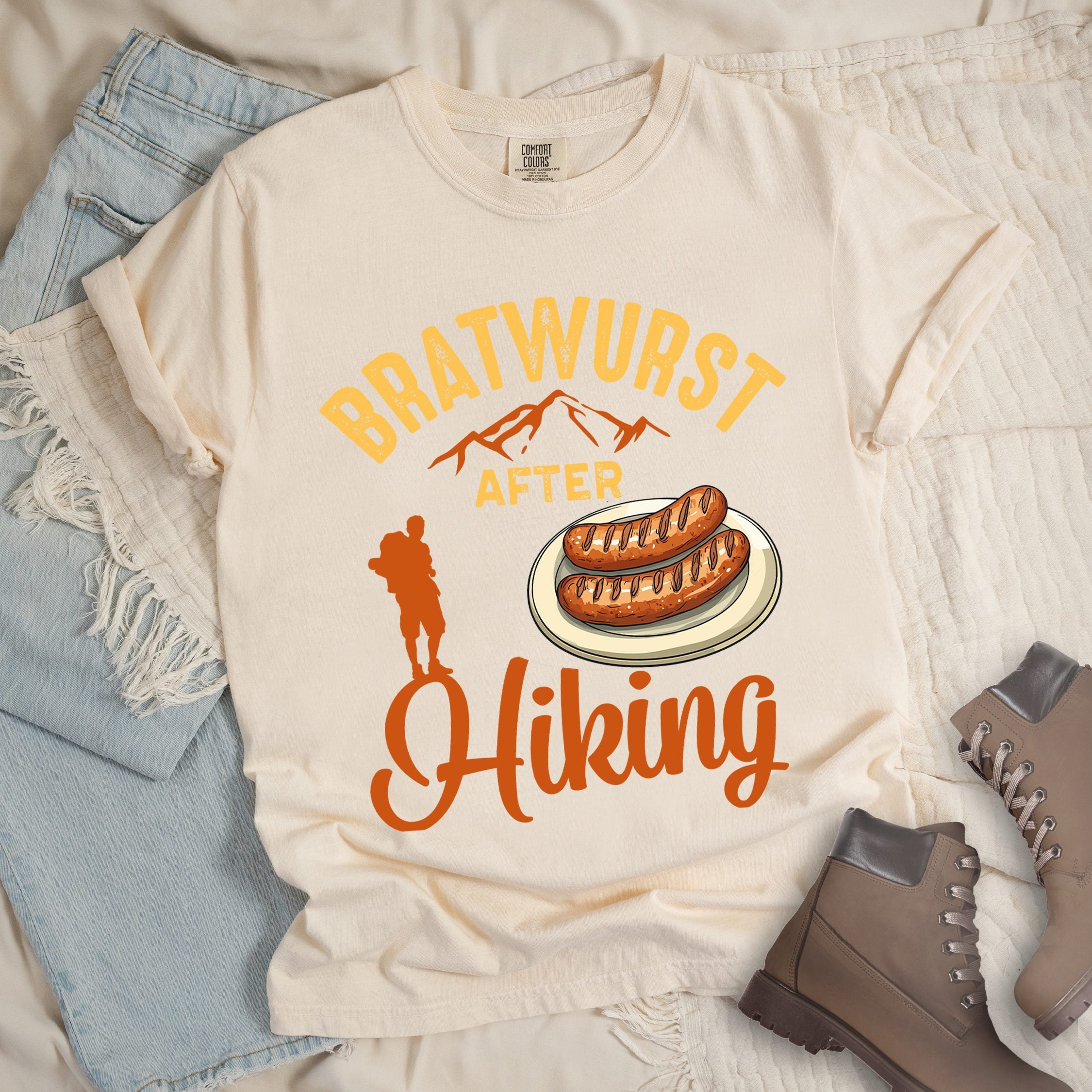 Ivory shirt with Hiking Design featuring the phrase “Bratwurst After Hiking” and an illustration of grilled bratwurst on a plate.