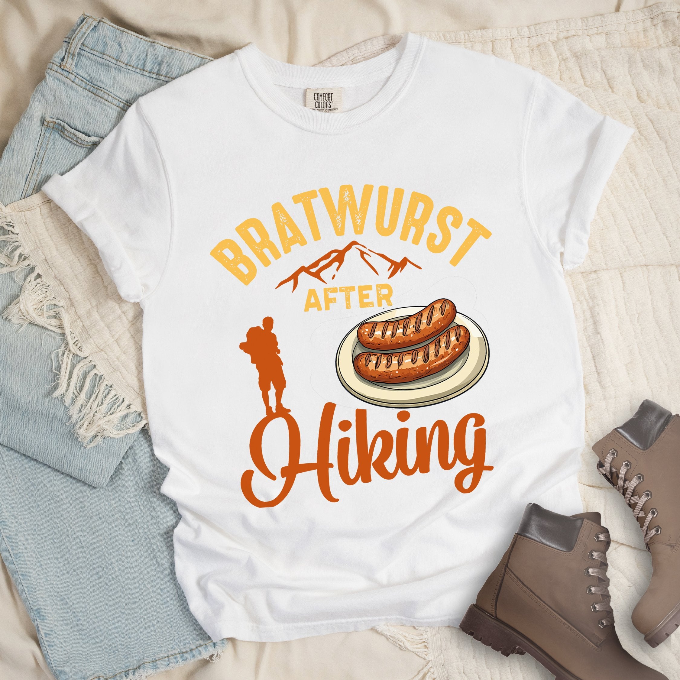 White shirt with Hiking Design featuring the phrase “Bratwurst After Hiking” and an illustration of grilled bratwurst on a plate.