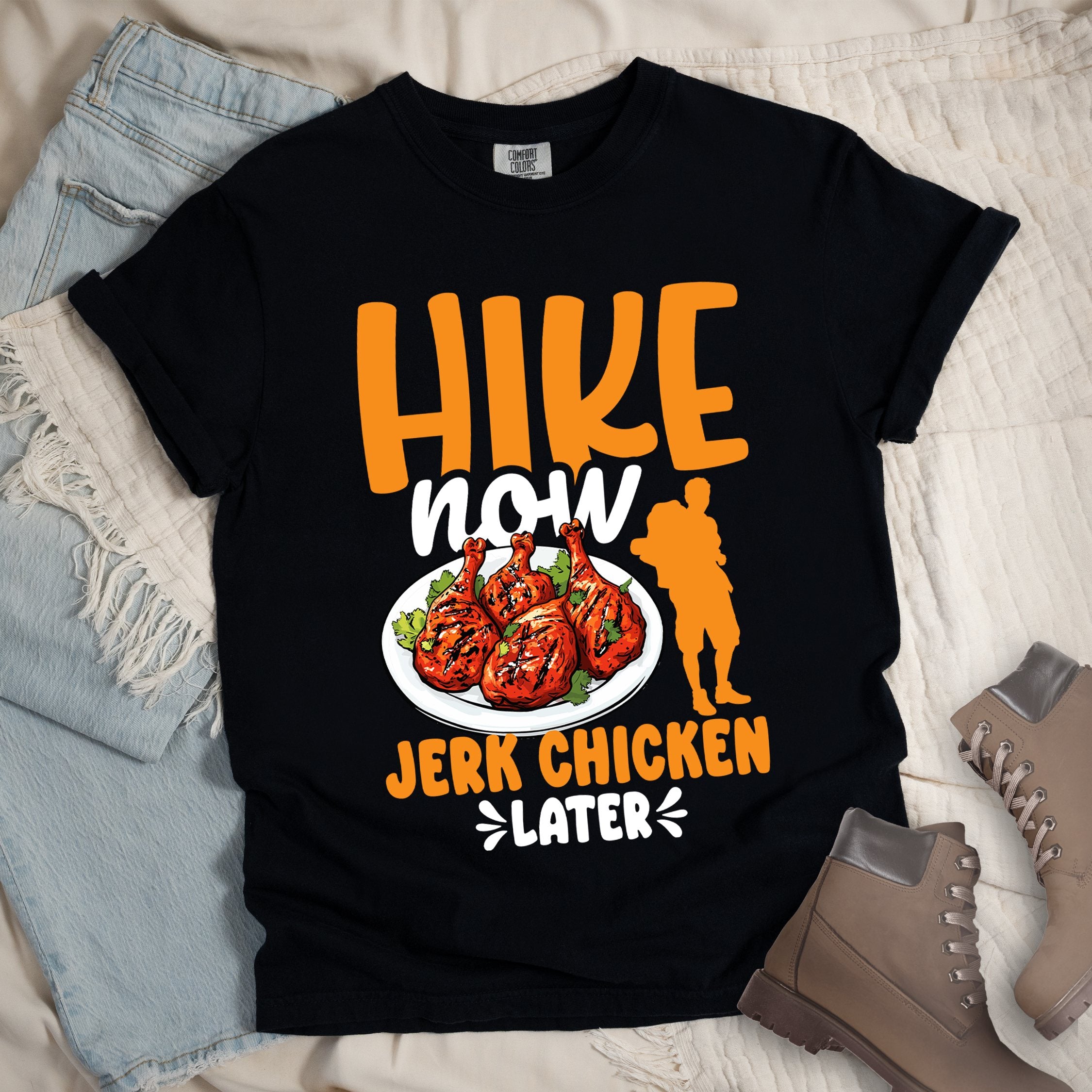 Black shirt with Hiking Design featuring the phrase “Hike Now Jerk Chicken Later” and an illustration of jerk chicken drumsticks.