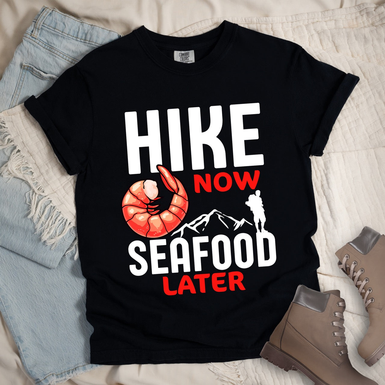 Funny hiking motivation shirt for seafood lovers featuring bold NOW LATER typography, realistic shrimp graphic, mountain landscape illustration, and hiker silhouette on premium outdoor adventure tee perfect gift for trail enthusiasts who love fresh ocean food in black