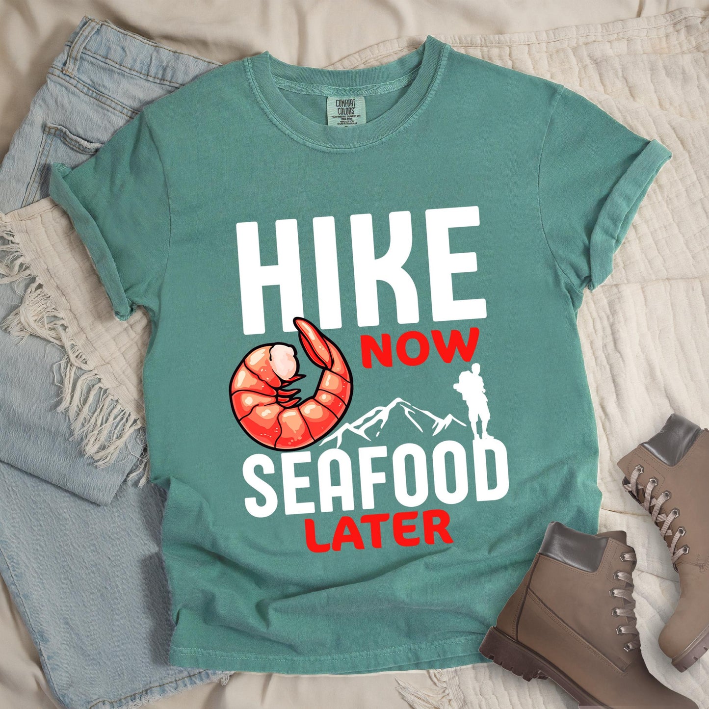 Green shirt with Hiking Design featuring the phrase “Hike Now Seafood Later” and an illustration of a shrimp with a mountain outline.