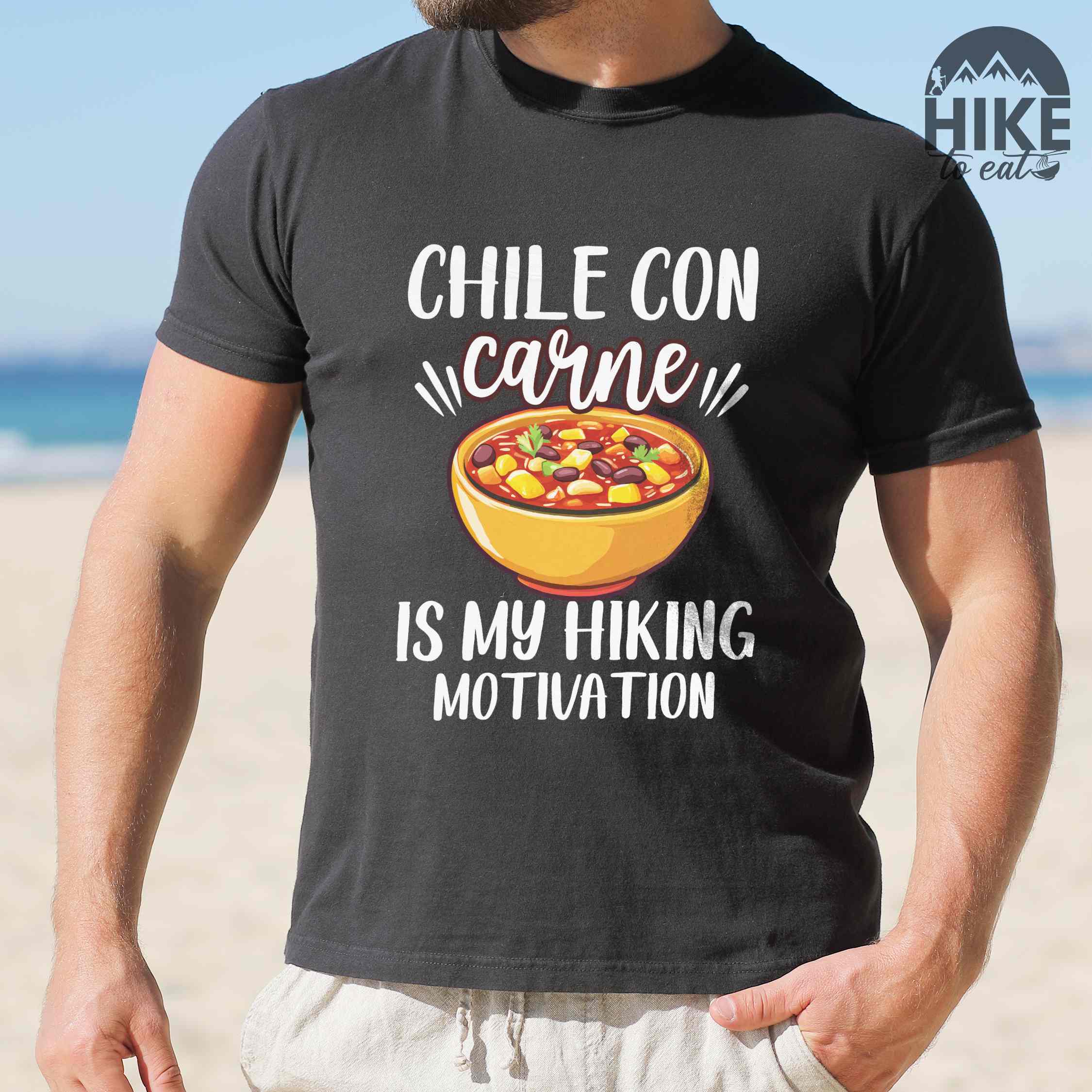 Man wearing black Chile con carne is my Hiking Motivation statement tee with bold typography, script lettering, and colorful chili bowl illustration for comfort food-loving outdoor enthusiasts