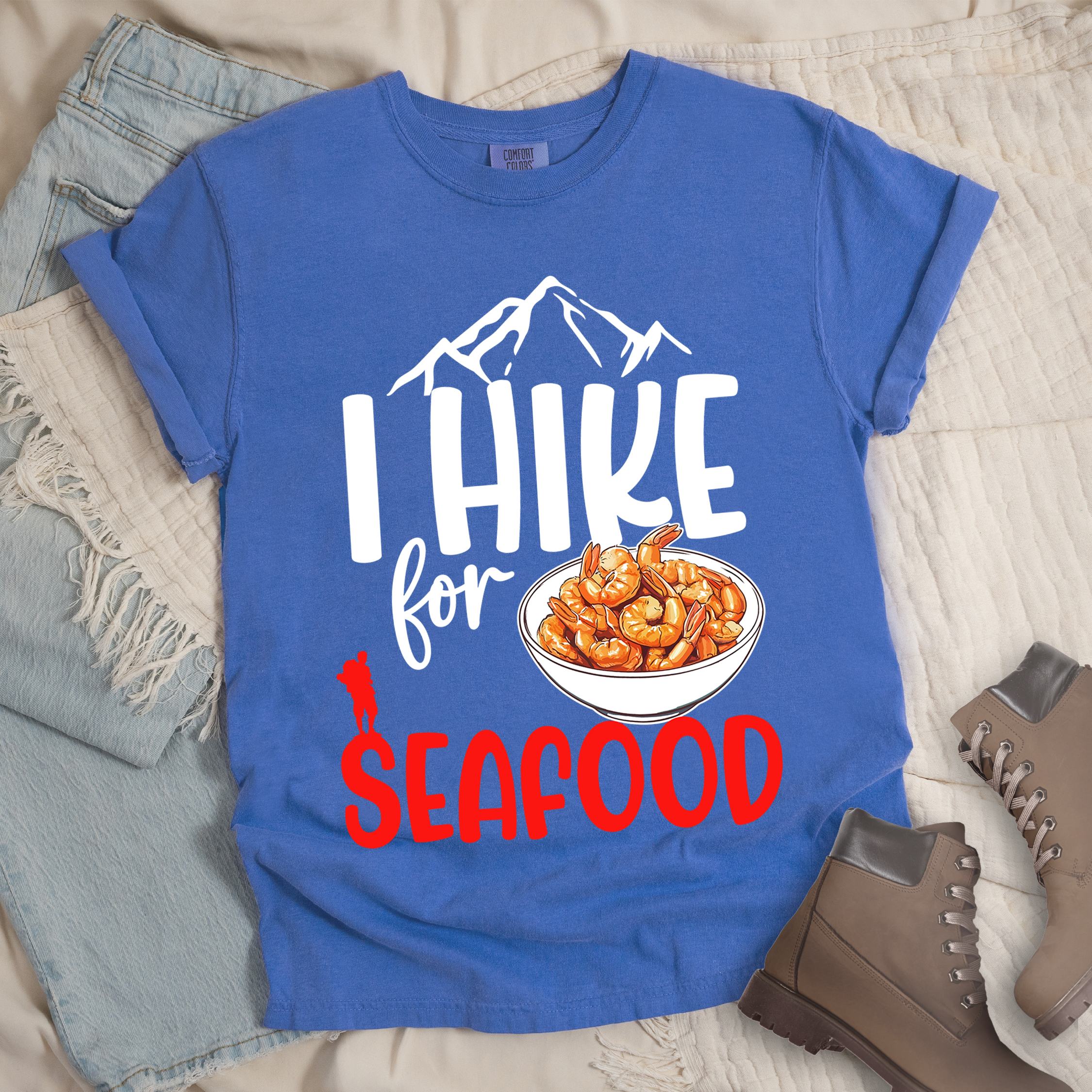 Blue shirt with Hiking Design featuring the phrase “I Hike for Seafood” and an illustration of a bowl of shrimp with a hiker silhouette.