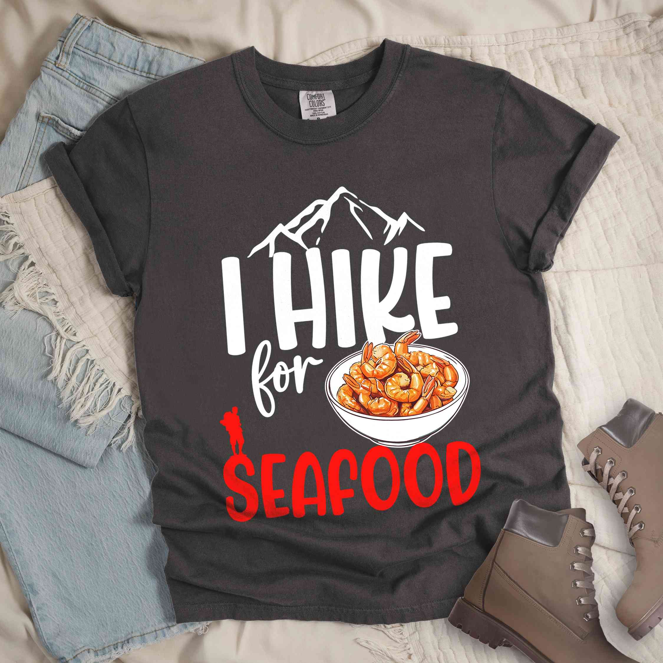 Pepper "I hike for seafood" colored vintage tee with bold typography, illustrated shrimps on a bowl, mountains, birds, and backpackers for seafood lovers.