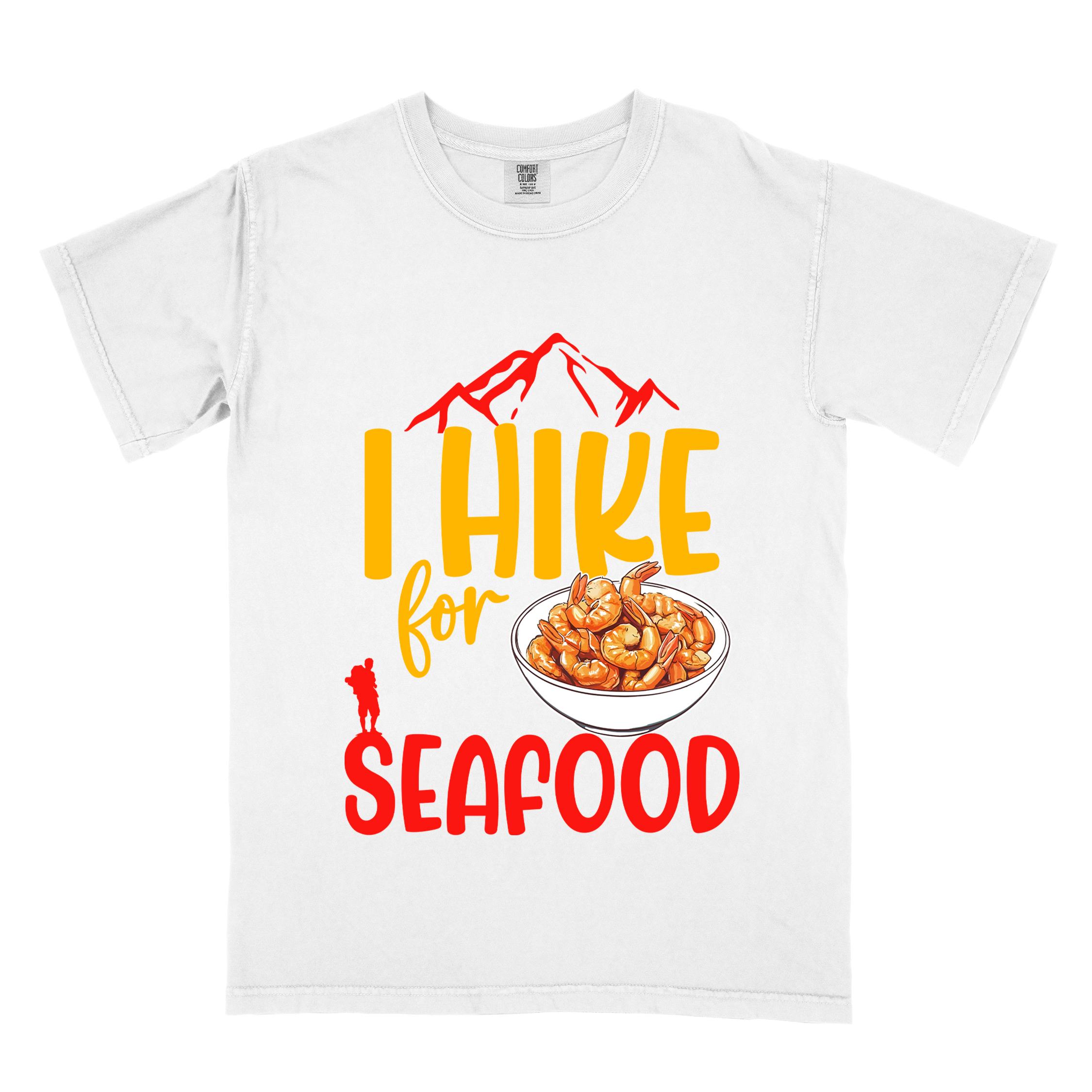 White "I hike for seafood" colored vintage tee with bold typography, illustrated shrimps on a bowl, mountains, birds, and backpackers for seafood lovers.