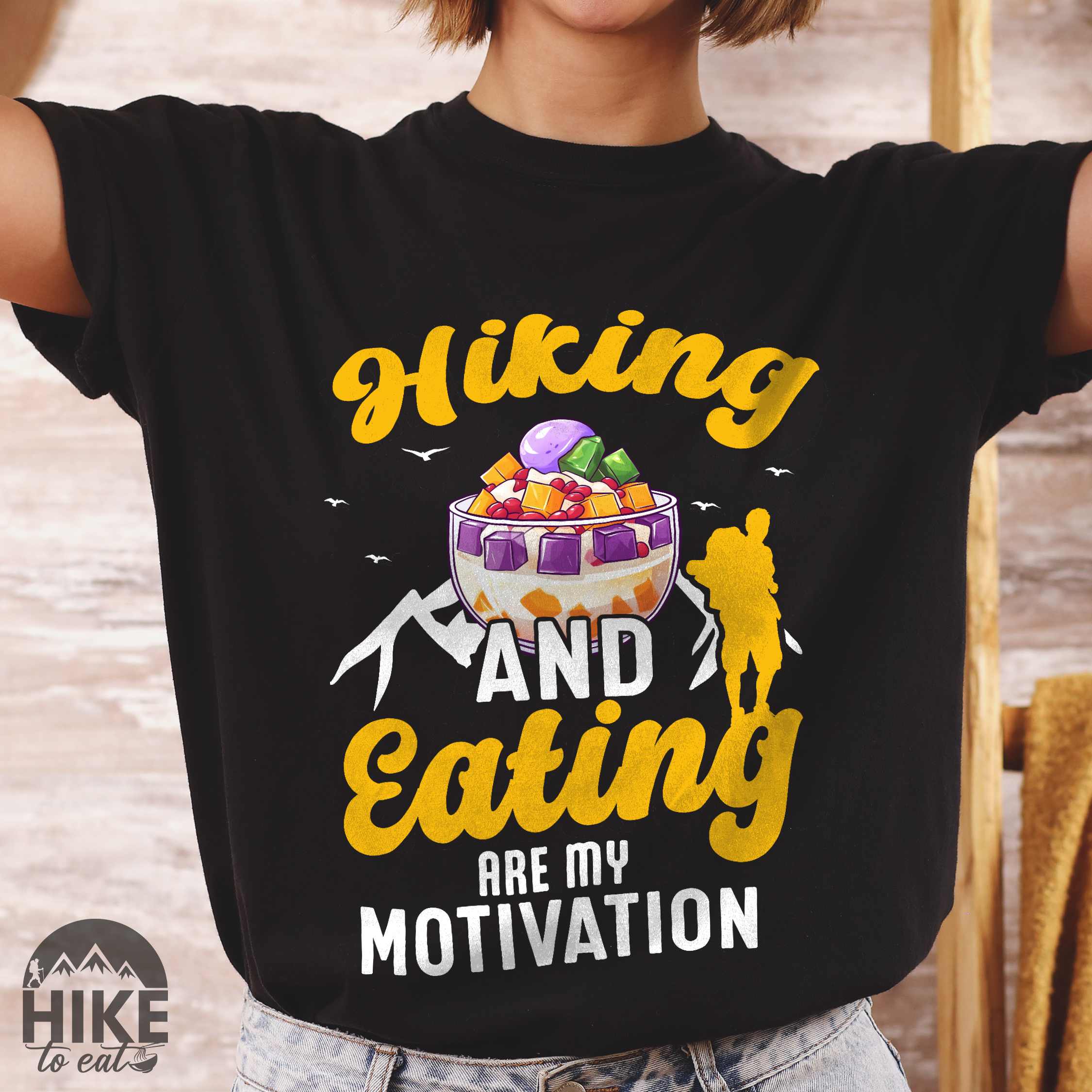 woman wearing black "hiking and eating are my motivation" colored vintage tee with bold typography, illustrated halo-halo dessert, and backpackers for filipino dessert lovers.