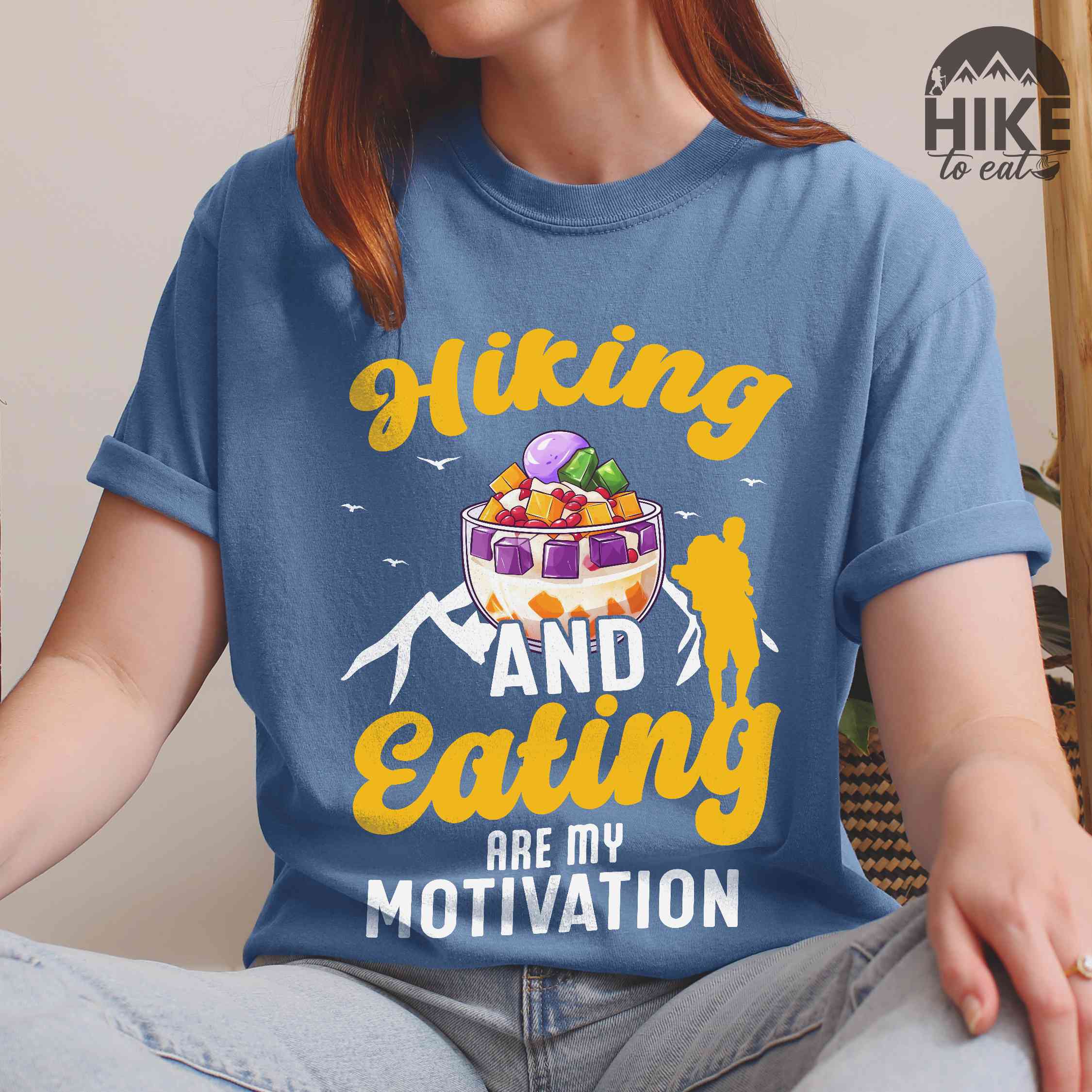 Woman wearing blue jean "hiking and eating are my motivation" colored vintage tee with bold typography, illustrated halo-halo dessert, and backpackers for filipino dessert lovers.