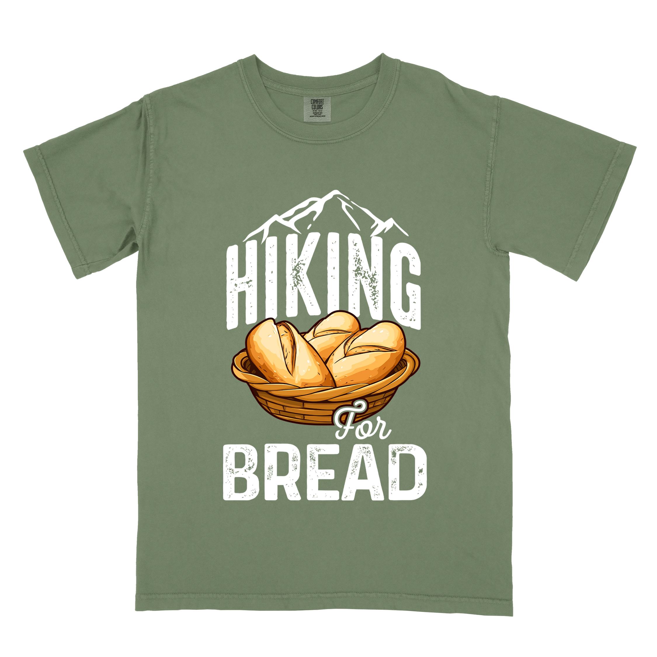 Moss "Hiking for bread" colored statement tee with flowing script typography, bold lettering, and freshly baked bread illustration for pastry-loving outdoor enthusiasts, hikers and foodies