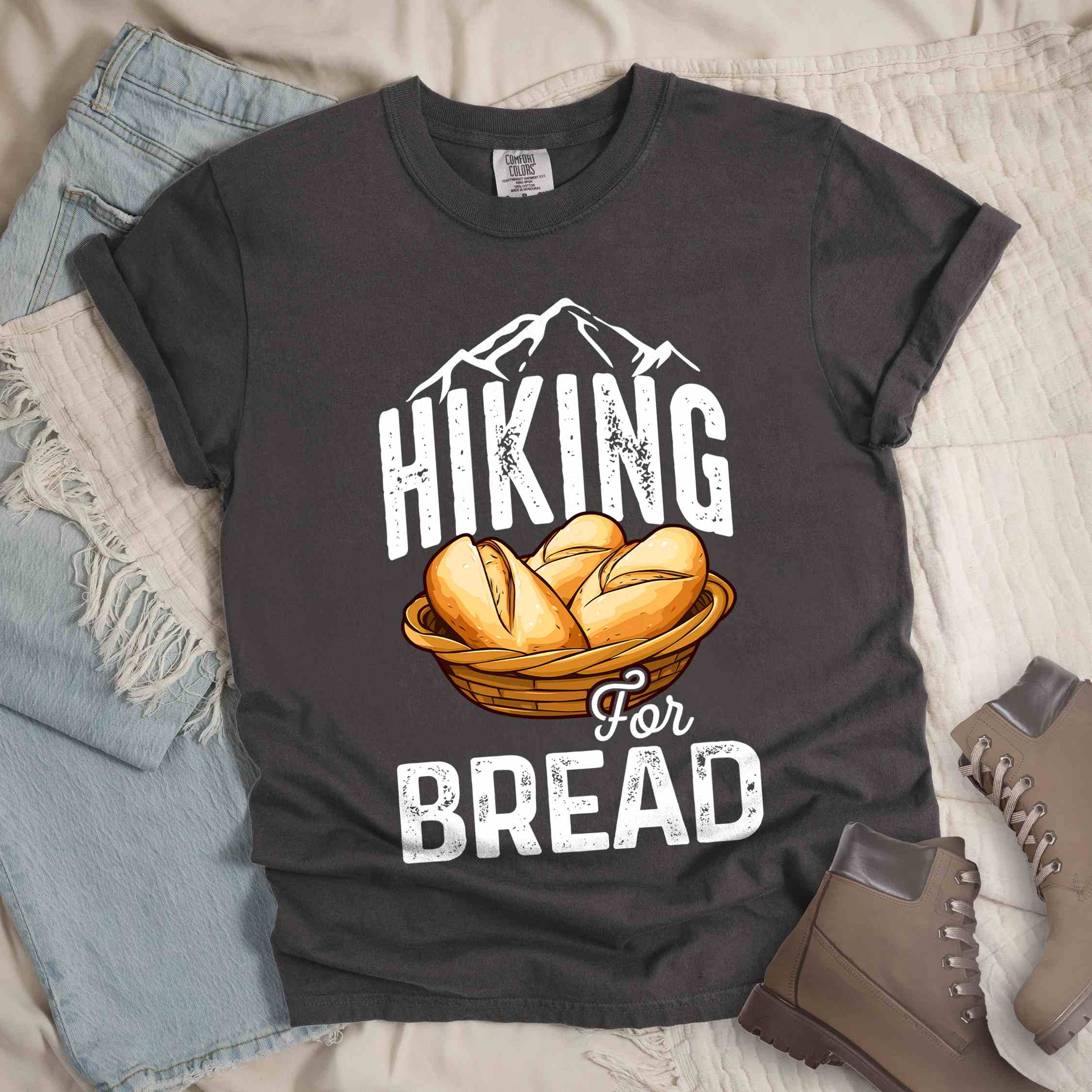 Pepper "Hiking for bread" colored statement tee with flowing script typography, bold lettering, and freshly baked bread illustration for pastry-loving outdoor enthusiasts, hikers and foodies