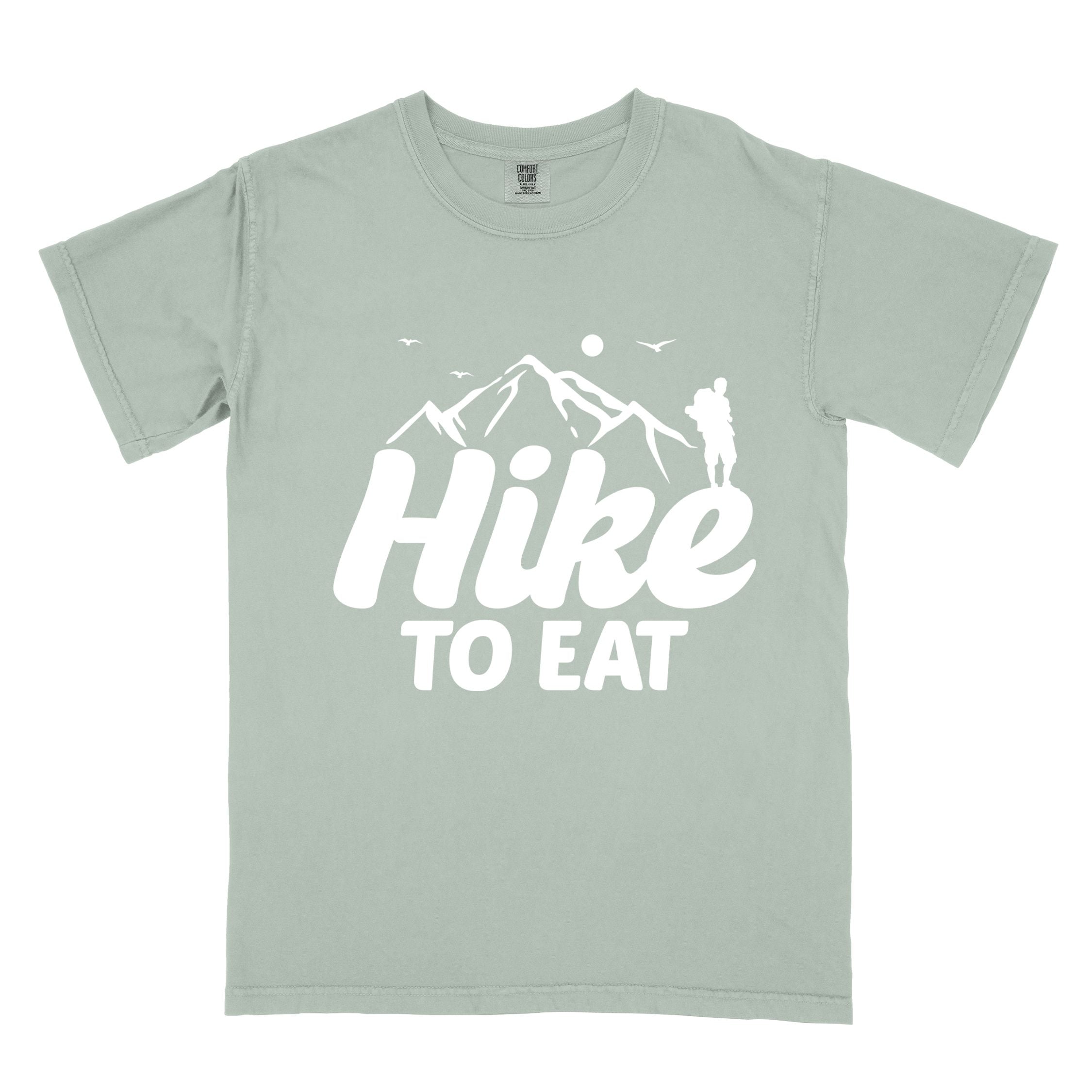 Bay "Hike to Eat" colored statement tee with bold typography, mountains, birds, sunrise, perfect for food motivated individuals.