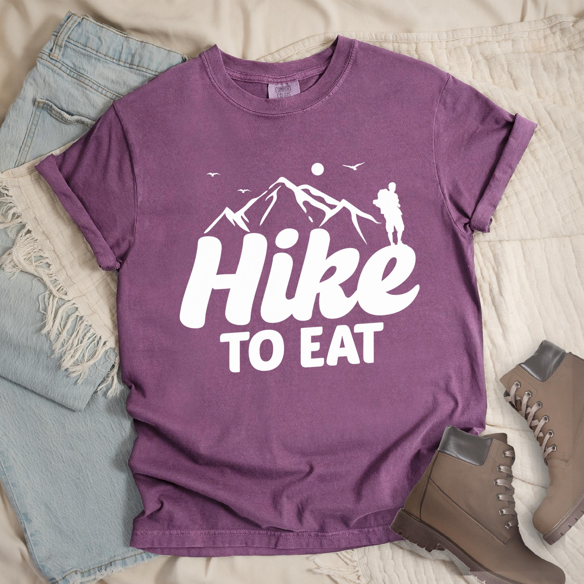 Dark pink shirt with Hiking Design featuring the phrase “Hike To Eat” showing a hiker silhouette and mountain illustration.