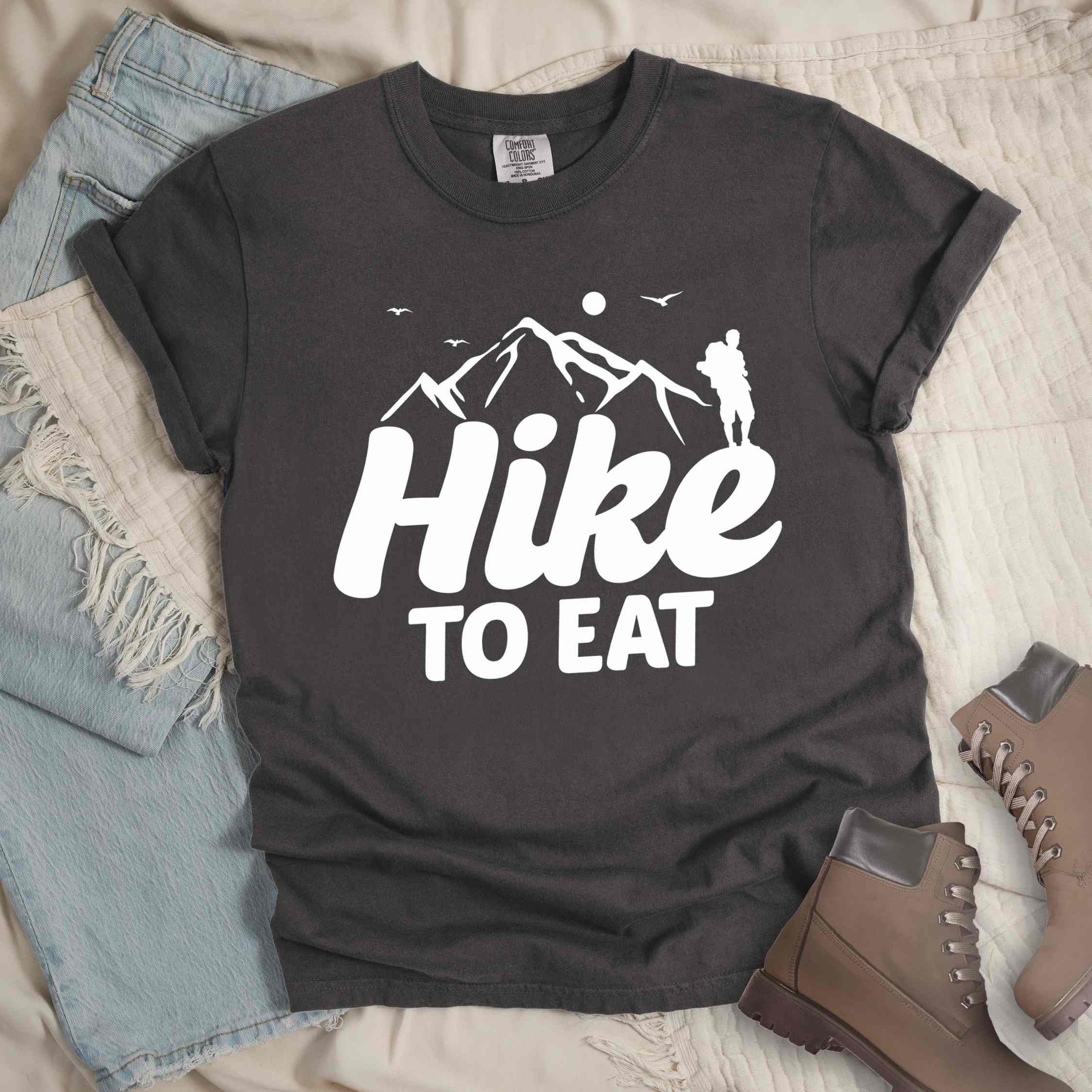 pepper "Hike to Eat" colored statement tee with bold typography, mountains, birds, sunrise, perfect for food motivated individuals.