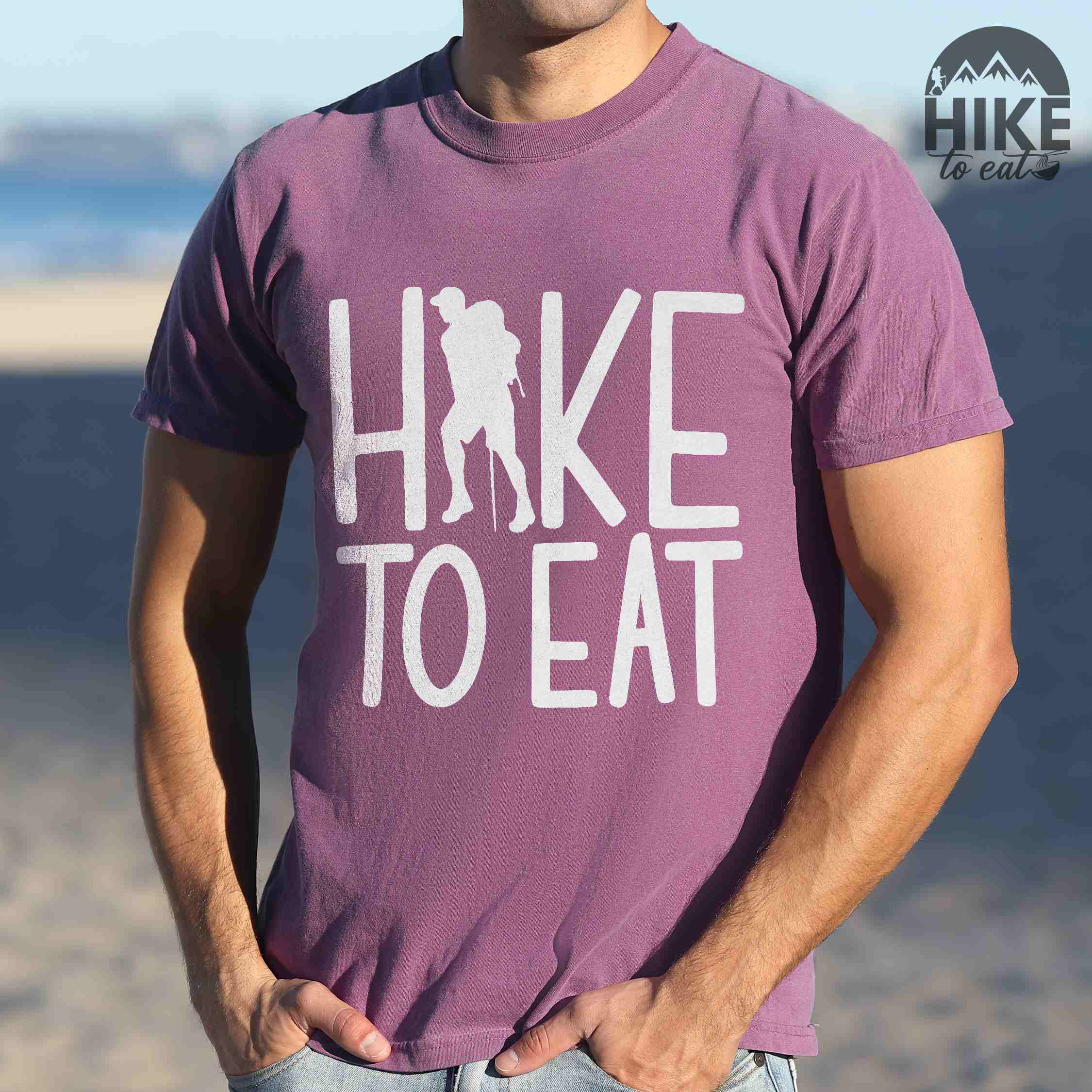 Man wearing berry "Hike to Eat" colored statement tee with bold typography, perfect for food motivated individuals.