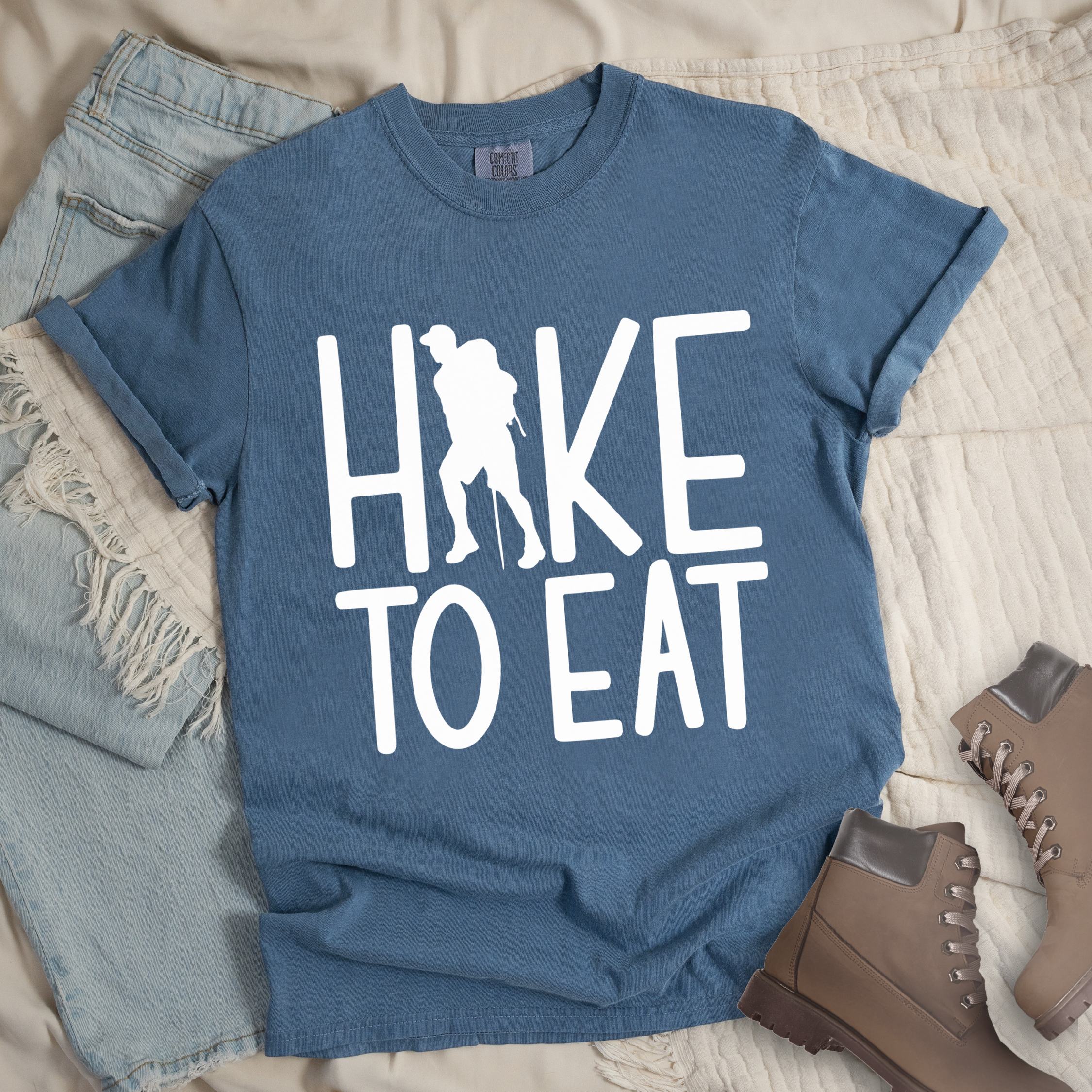Dark blue shirt with Hiking Design featuring the phrase “Hike To Eat” and a large hiker silhouette standing inside the letter “H.”