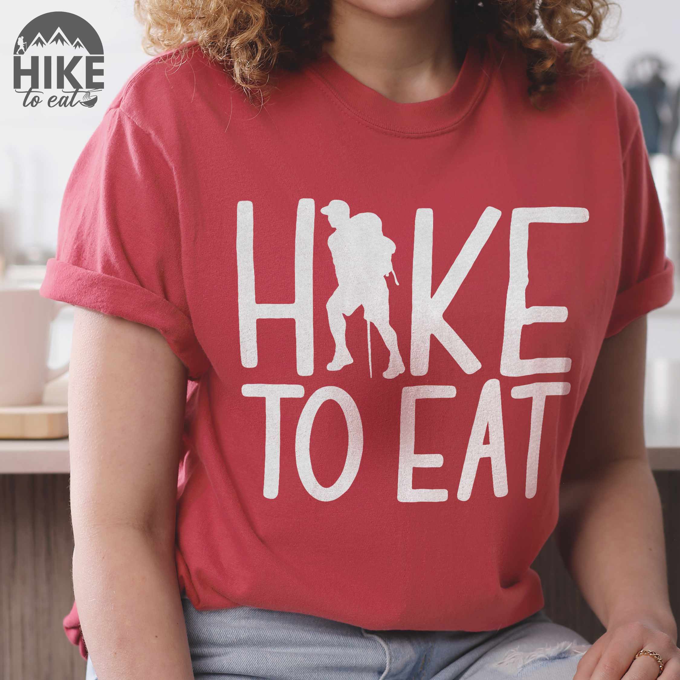 Woman wearing crimson "Hike to Eat" colored statement tee with bold typography, perfect for food motivated individuals.