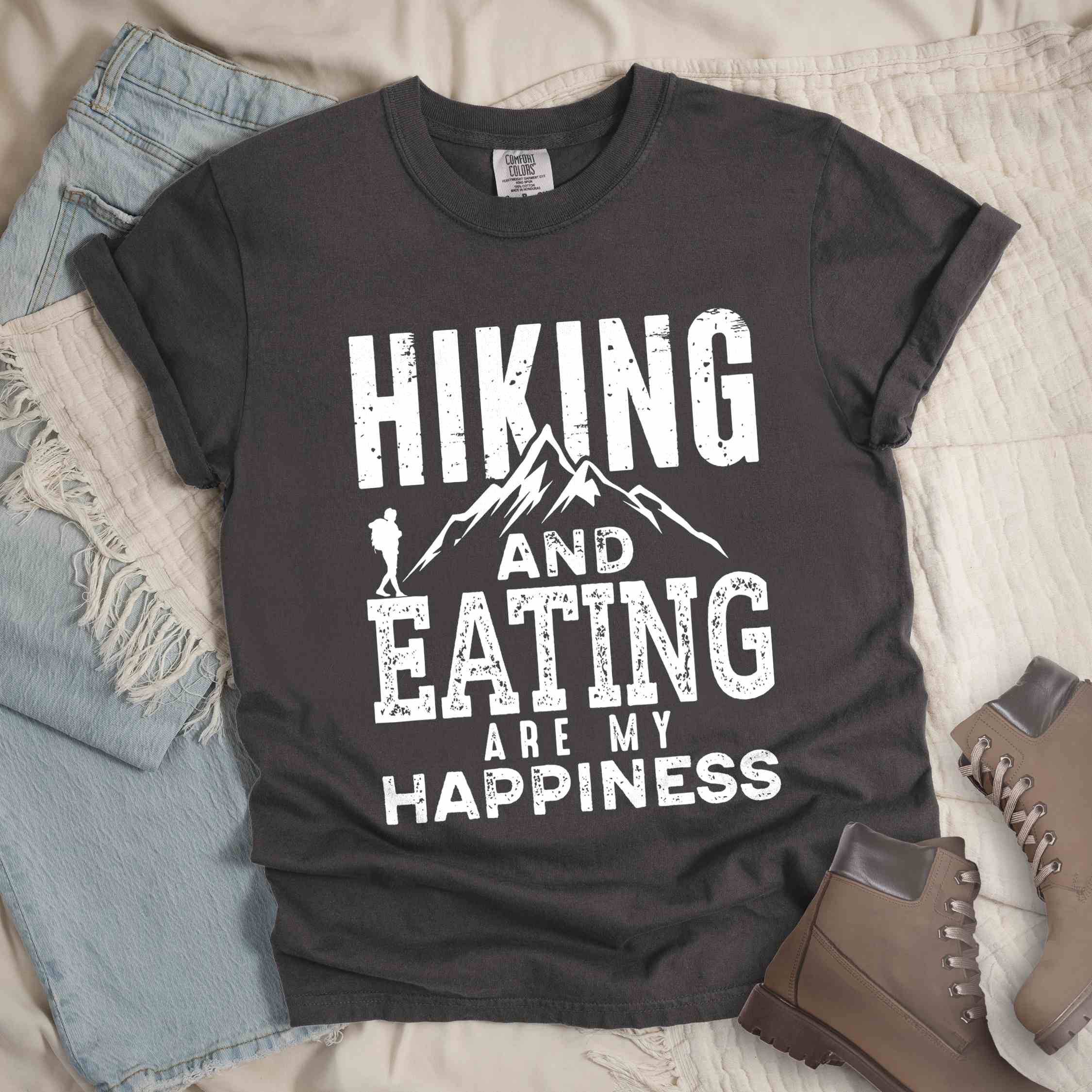 Pepper "Hiking and Eating are my happiness" colored statement tee with bold typography, mountains, birds, perfect for adventure motivated individuals.
