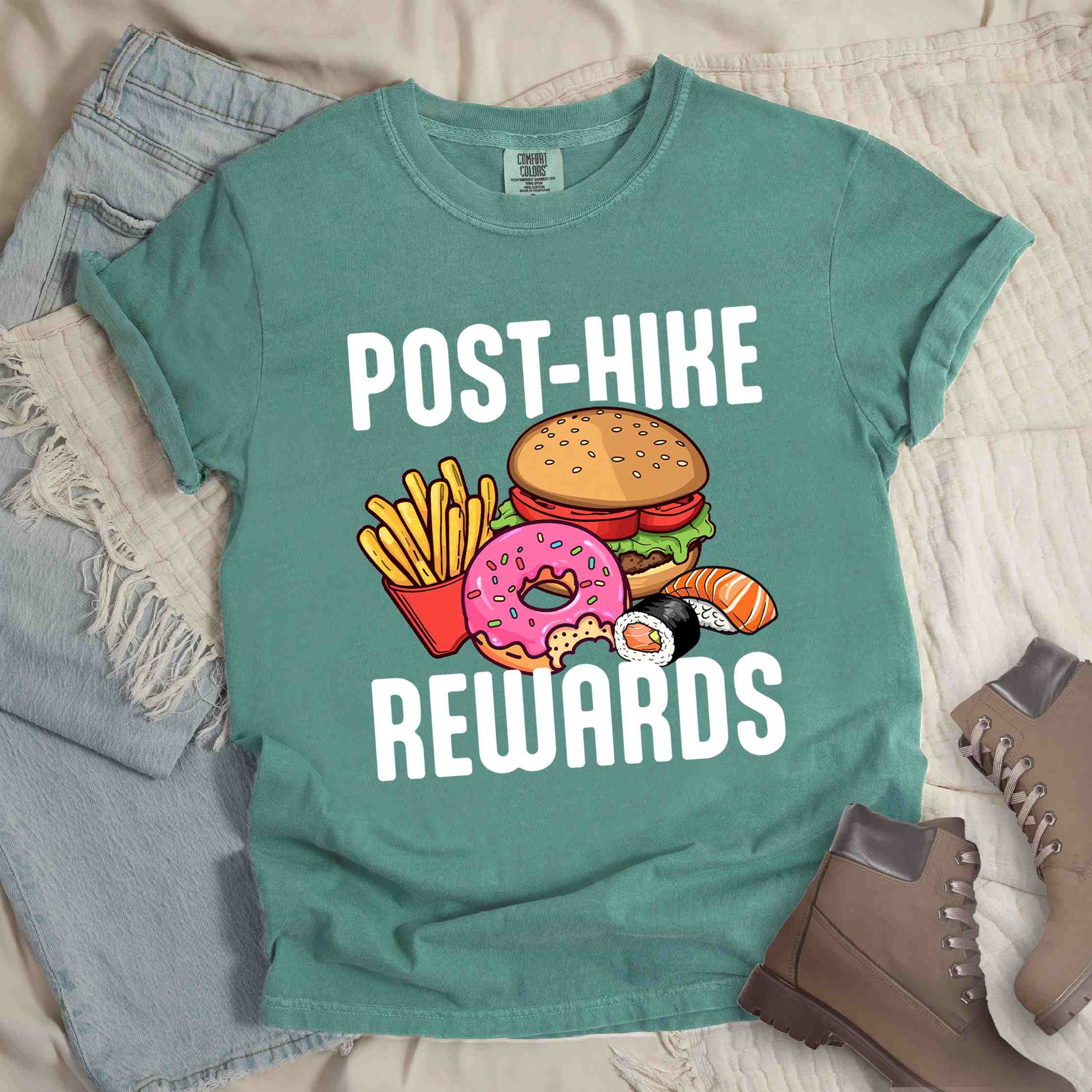 Light green "Post-hike rewards" colored statement tee with bold typography, mountains, birds, illustrated fast food meal, perfect for adventure motivated individuals and looking for post-hike meal.
