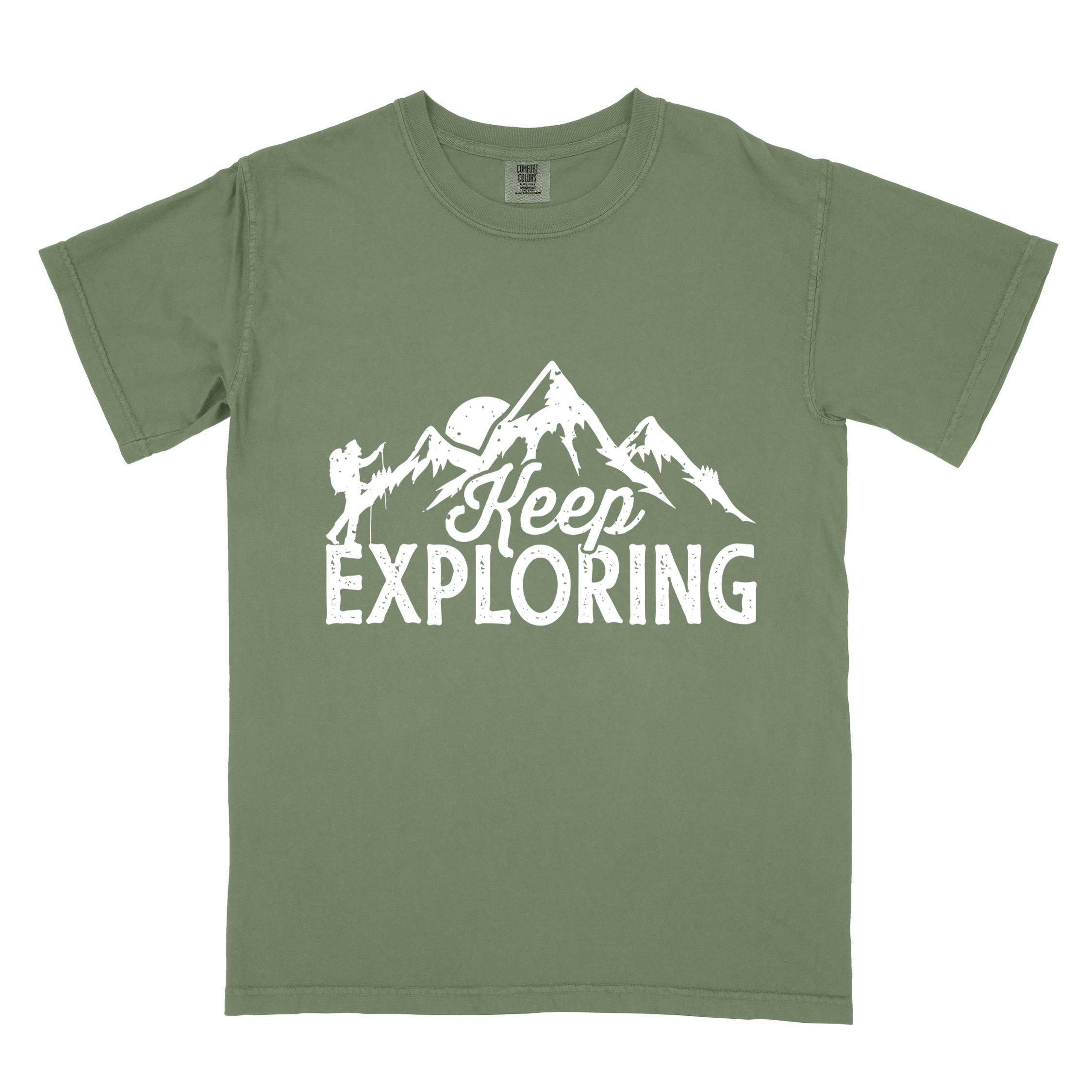 Moss "Keep Exploring" colored statement tee with bold typography, mountains, birds, perfect for adventure motivated individuals.