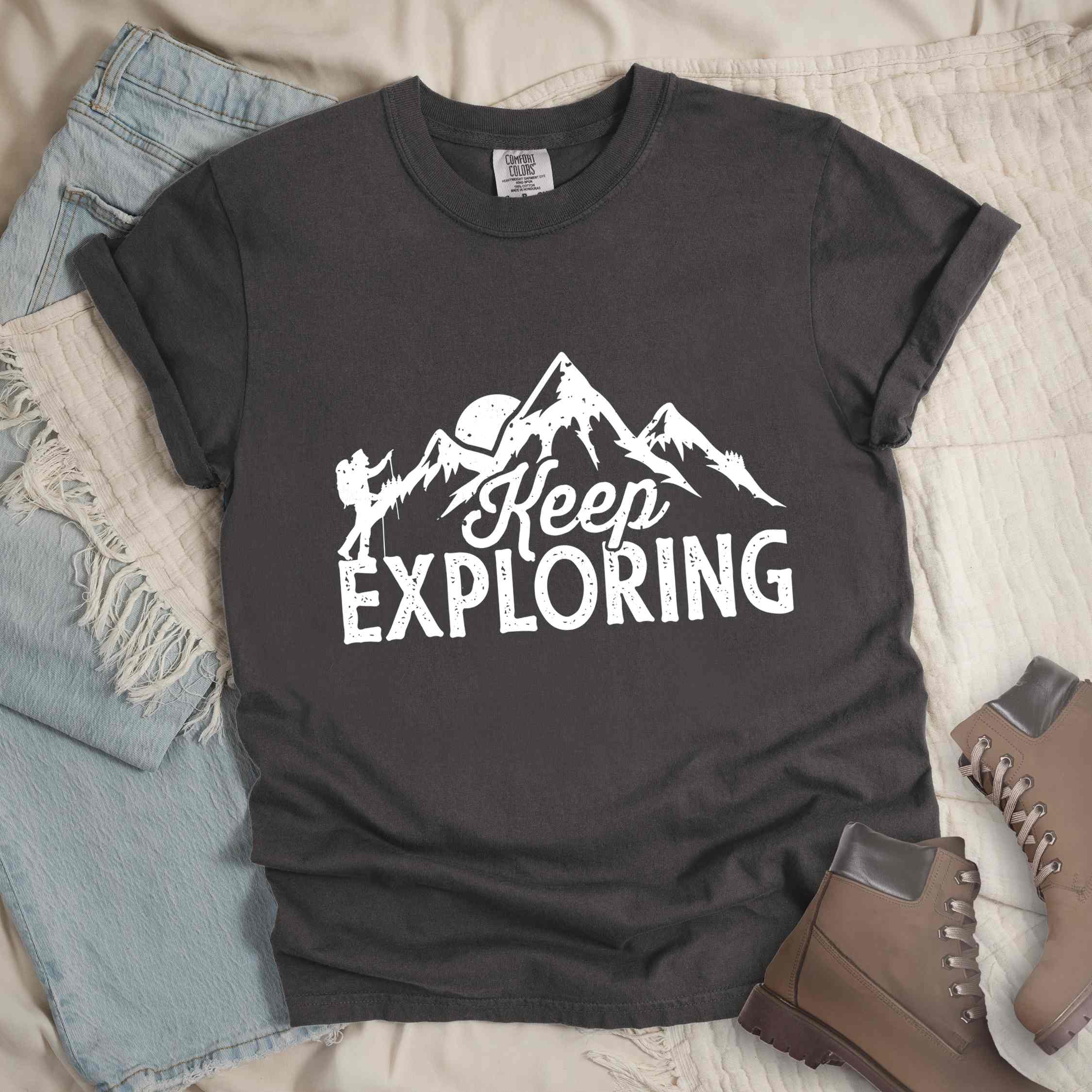 Pepper "Keep Exploring" colored statement tee with bold typography, mountains, birds, perfect for adventure motivated individuals.