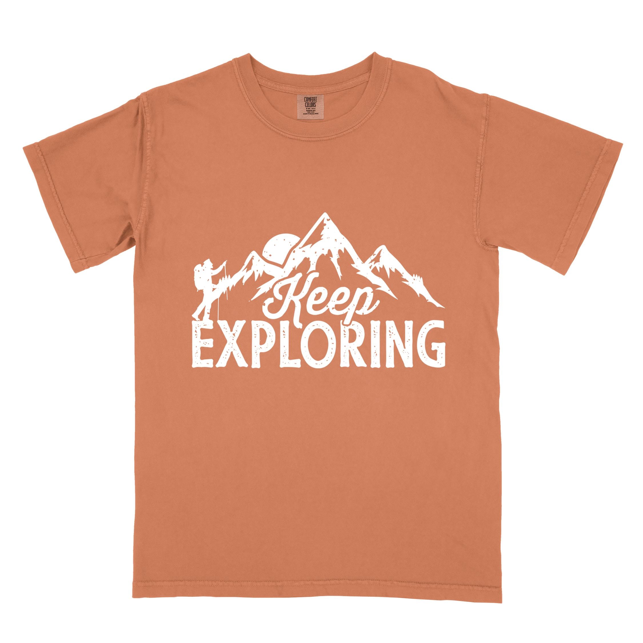 Yam "Keep Exploring" colored statement tee with bold typography, mountains, birds, perfect for adventure motivated individuals.