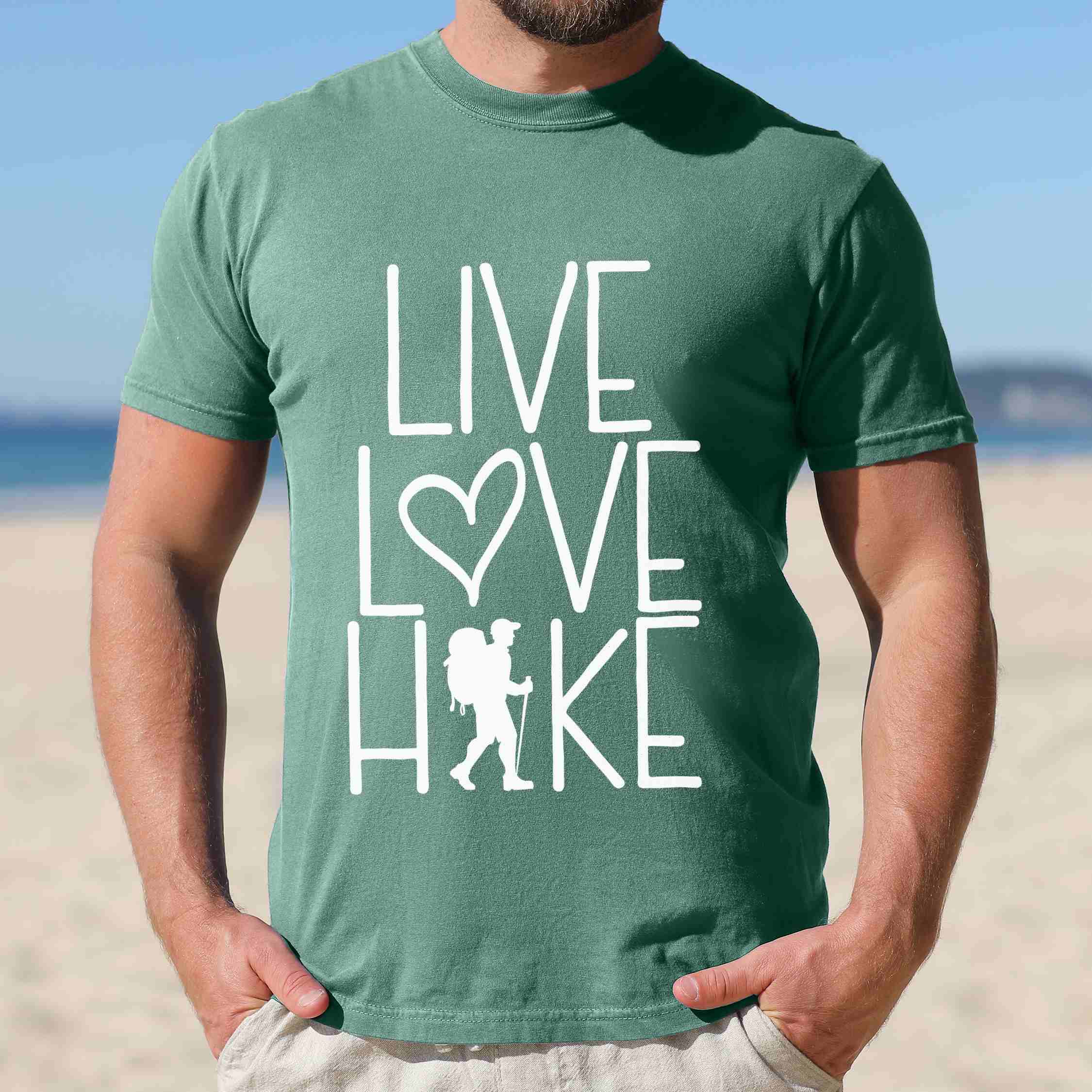Man wearing light green "Live Love hike" colored statement tee with bold typography, perfect for adventure motivated individuals.