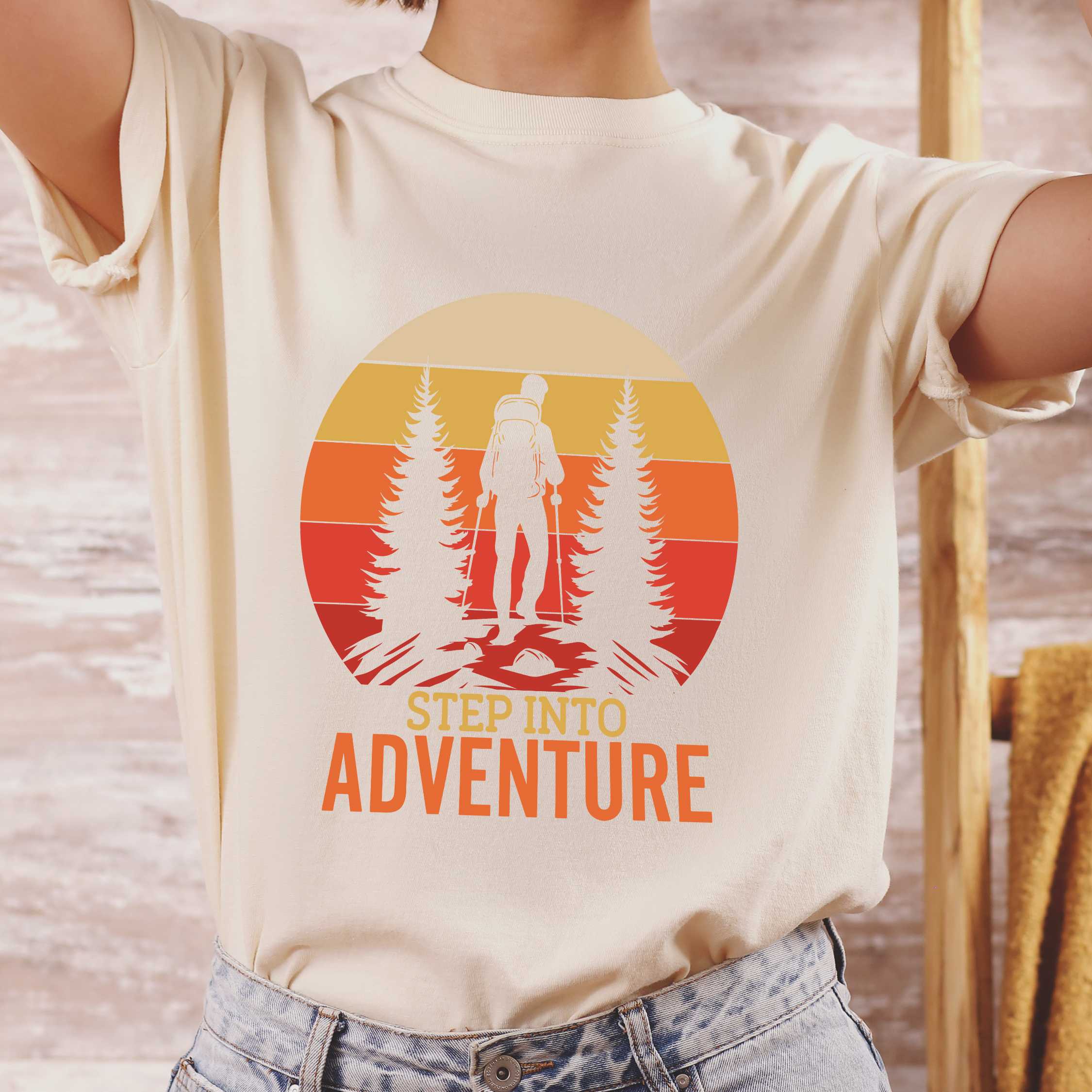 Woman wearing ivory "Step into adventure" colored statement tee with bold typography, mountain, sunrise, perfect for adventure motivated individuals.