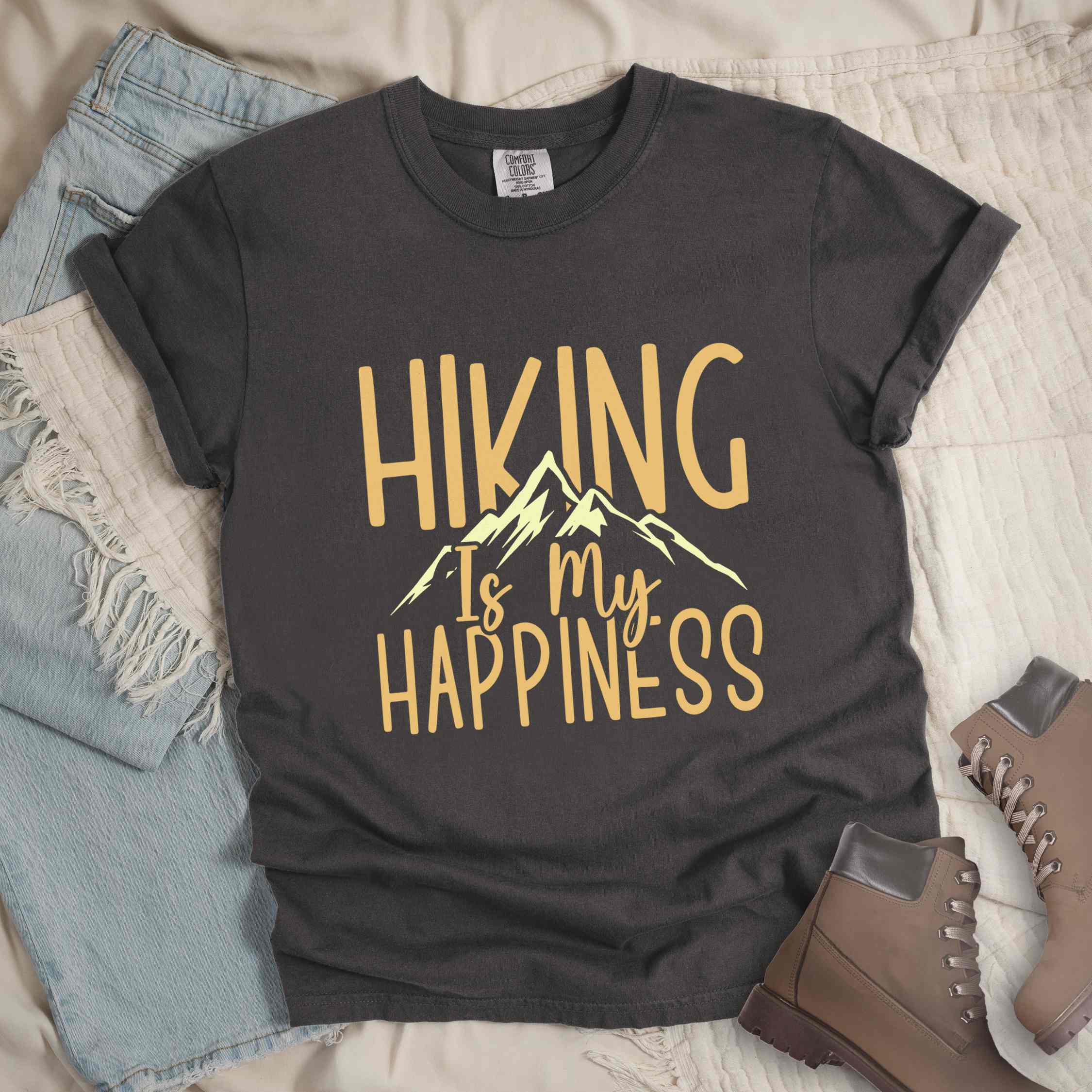 Pepper "hiking is my happiness" colored statement tee with bold typography, mountain, sunrise, perfect for adventure motivated individuals.