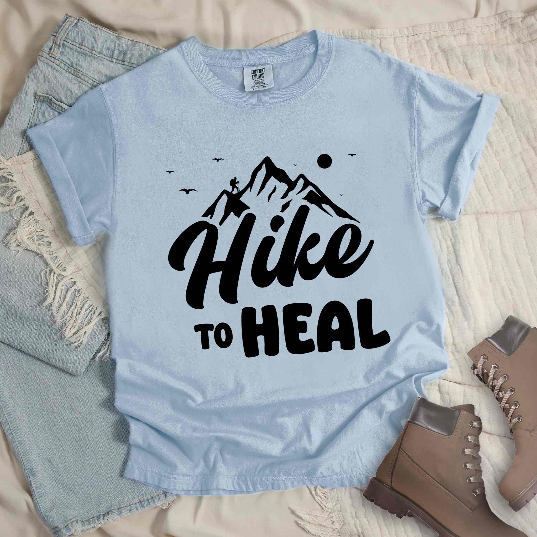 Chambray "Hike to Heal" colored statement tee with bold typography, mountain, sunrise, perfect for adventure driven individuals.