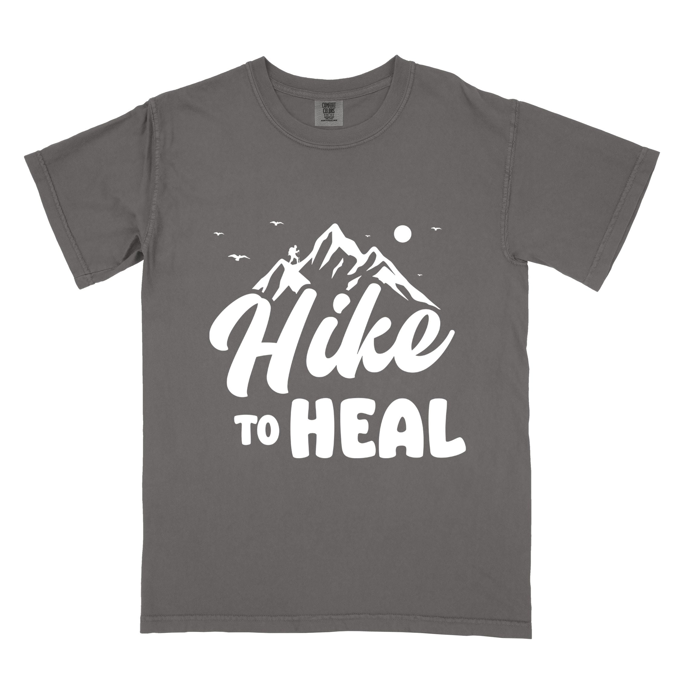 Pepper "Hike to Heal" colored statement tee with bold typography, mountain, sunrise, perfect for adventure driven individuals.