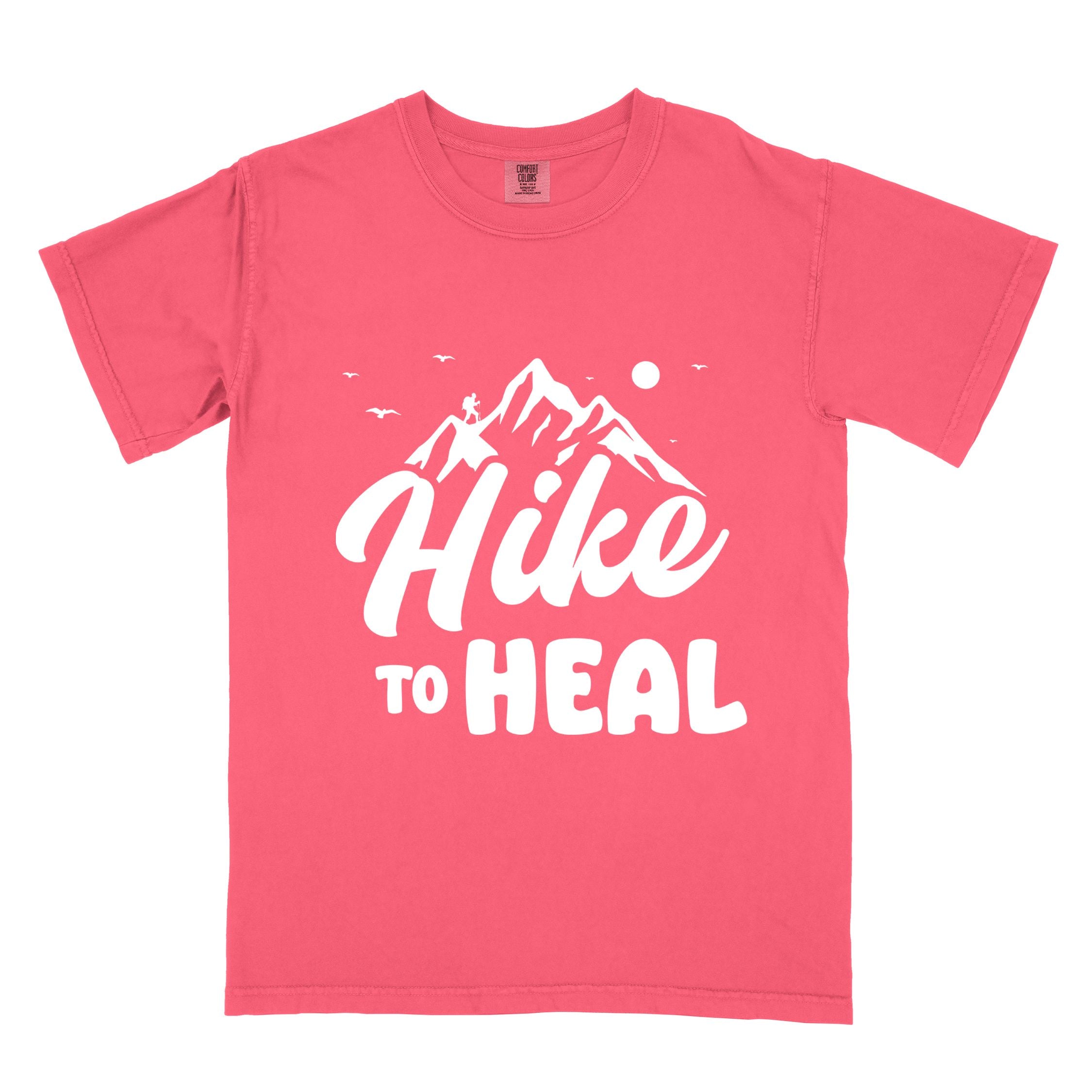 Watermelon "Hike to Heal" colored statement tee with bold typography, mountain, sunrise, perfect for adventure driven individuals.
